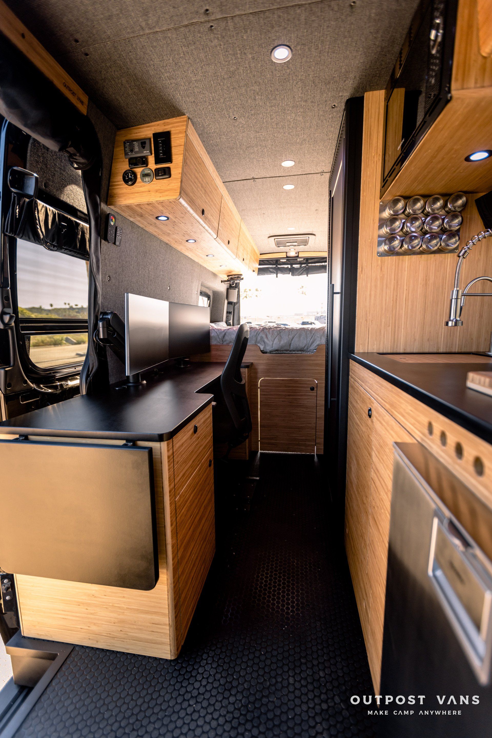 The inside of a camper van with a desk and a sink.
