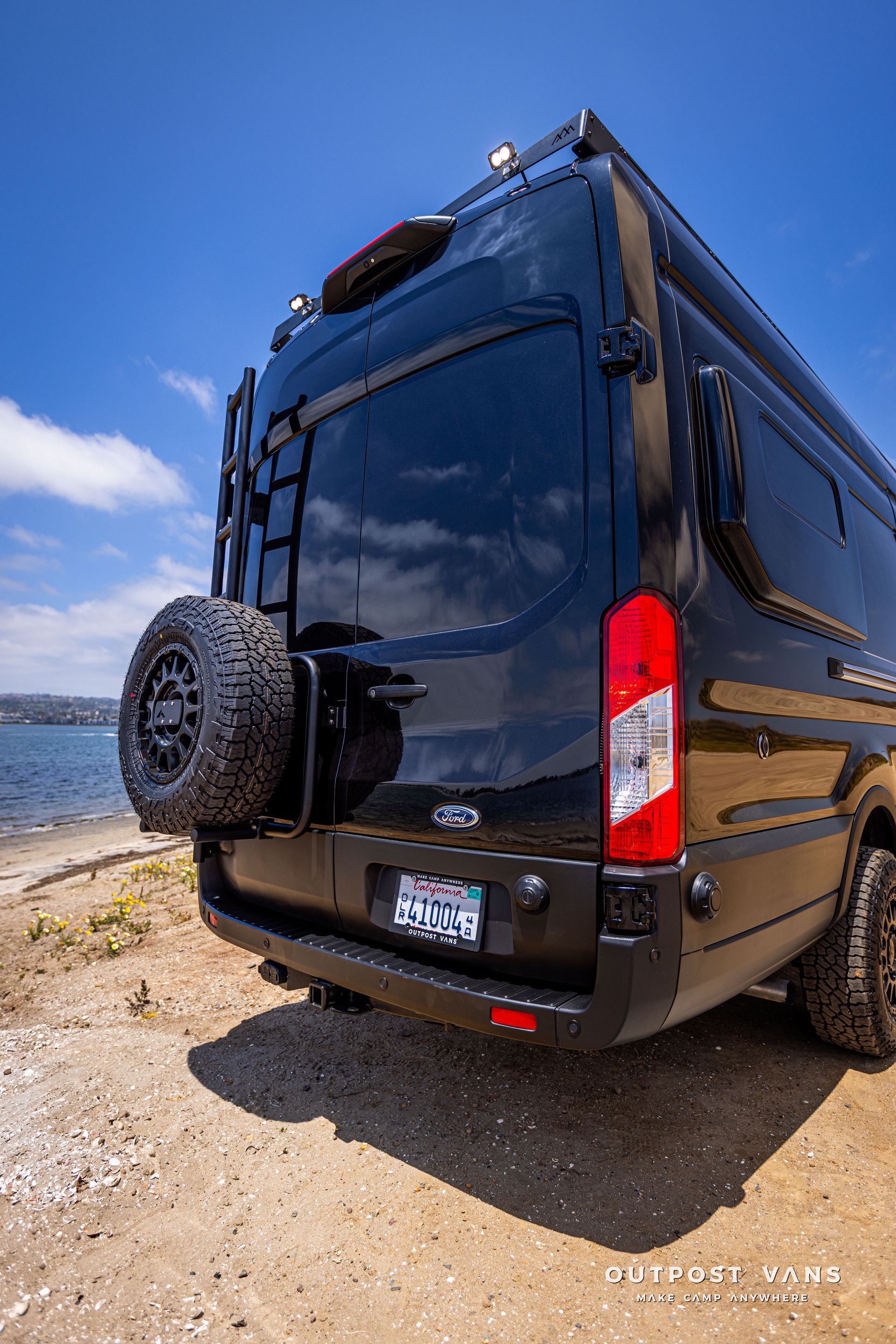 Outpost Vans custom built camper van Ford Transit 148 AWD. Aluminess rear door tire carrier / ladder