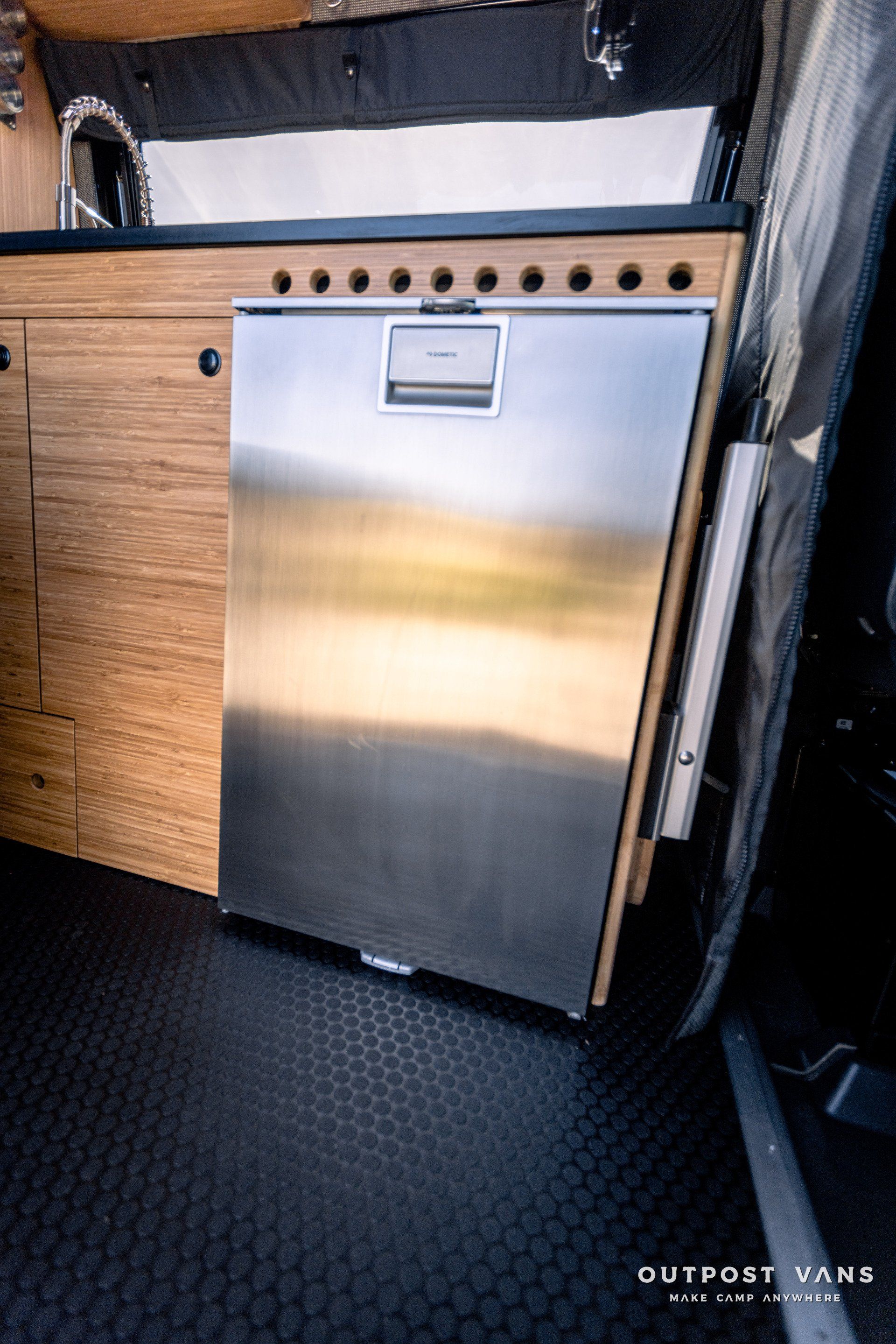 A stainless steel refrigerator is sitting next to a sink in a kitchen.