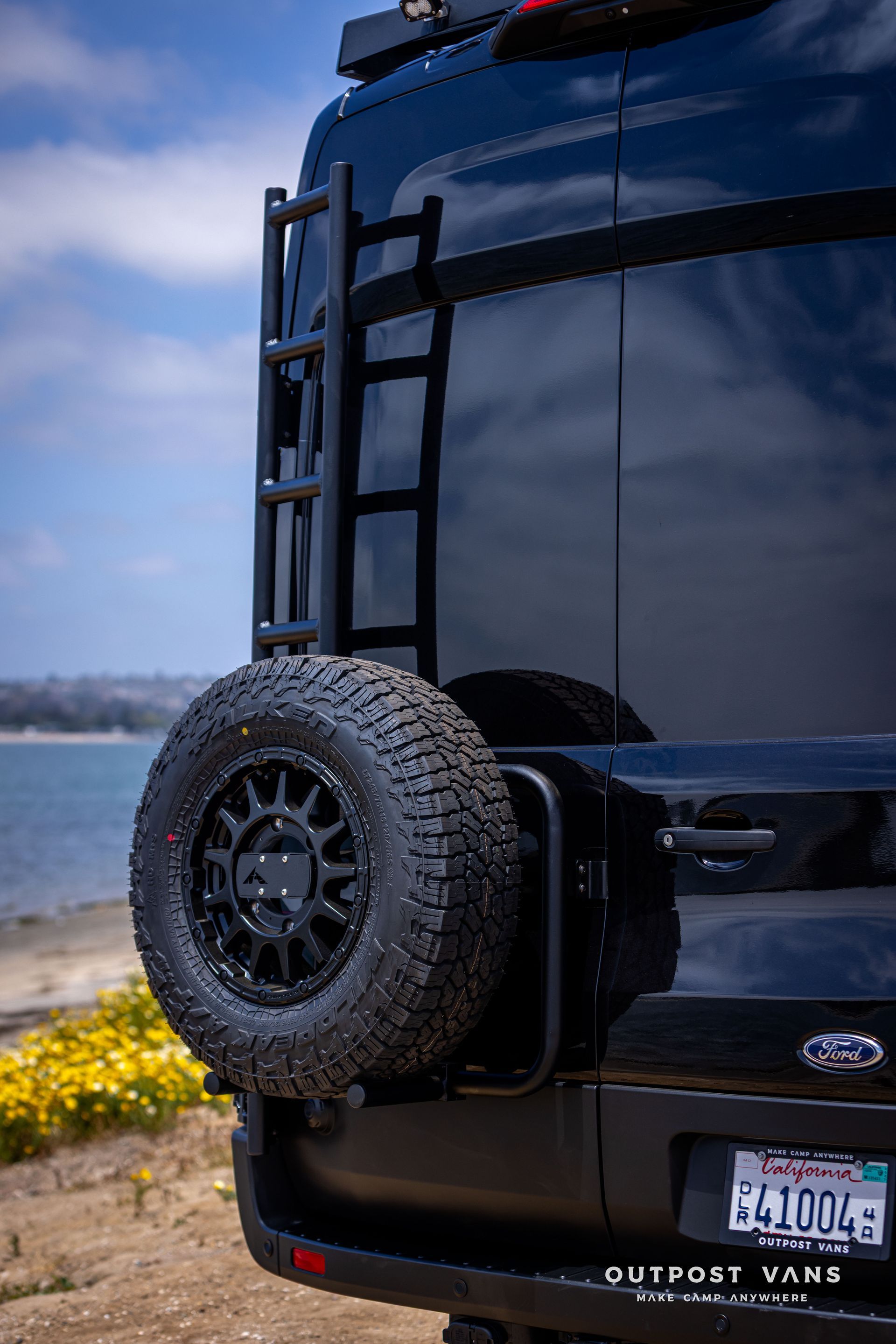 Outpost Vans custom built camper van Ford Transit 148 AWD. Aluminess rear door tire carrier / ladder