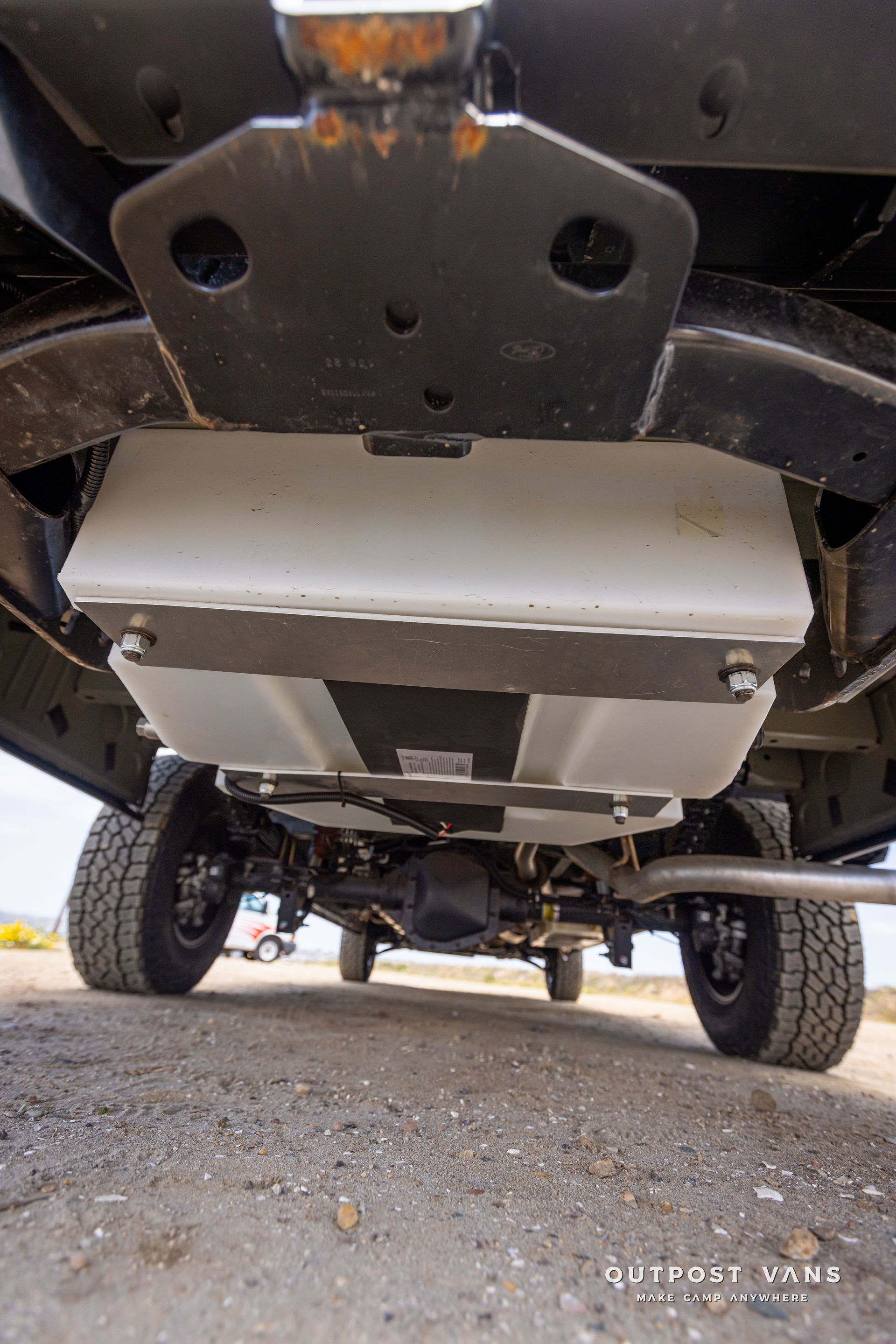 Outpost Vans custom built camper van Ford Transit 148 AWD. under van fresh water tank