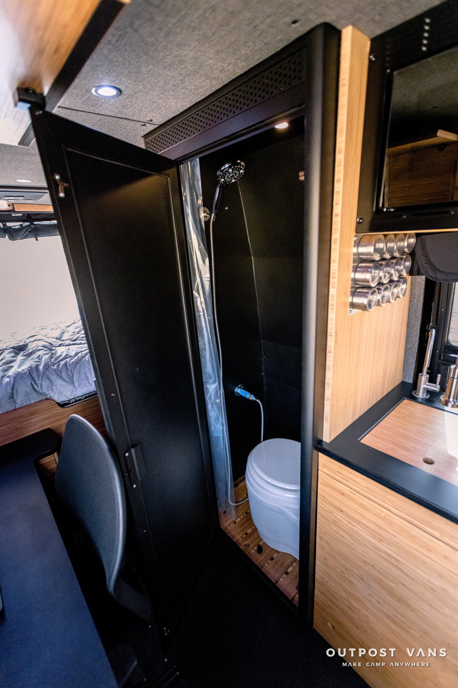 A bathroom in a van with a toilet and shower.