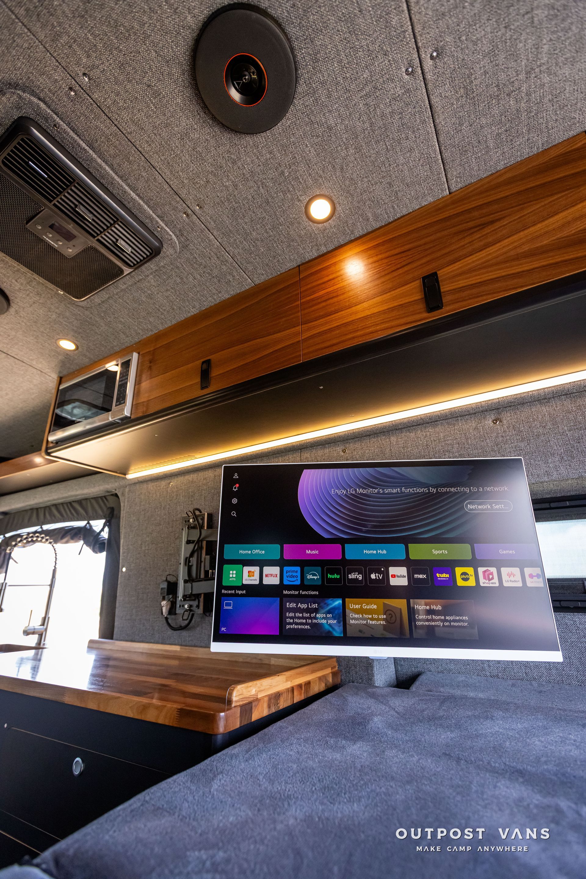 Outpost Vans custom built camper van Ford Transit 148 AWD. A flat screen tv is mounted to the ceiling of a van.