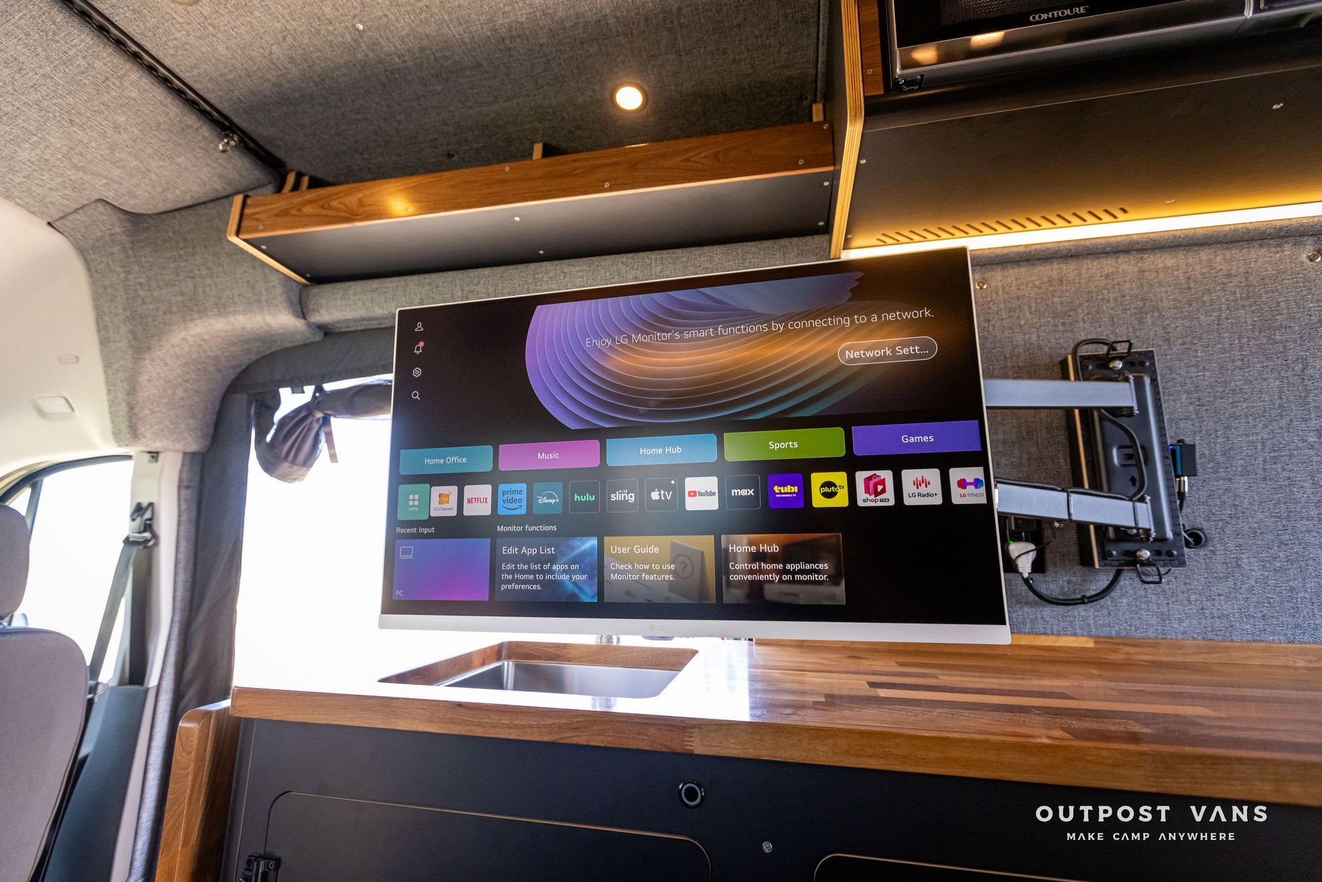 Outpost Vans custom built camper van Ford Transit 148 AWD. A flat screen tv is mounted to the ceiling of a van.