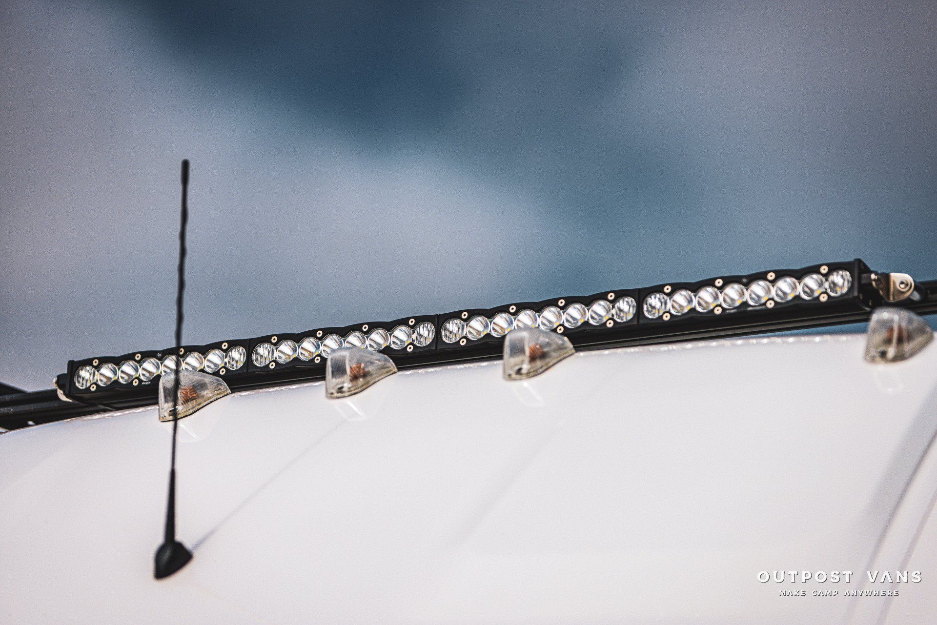a white van with a light bar and antenna on the roof .