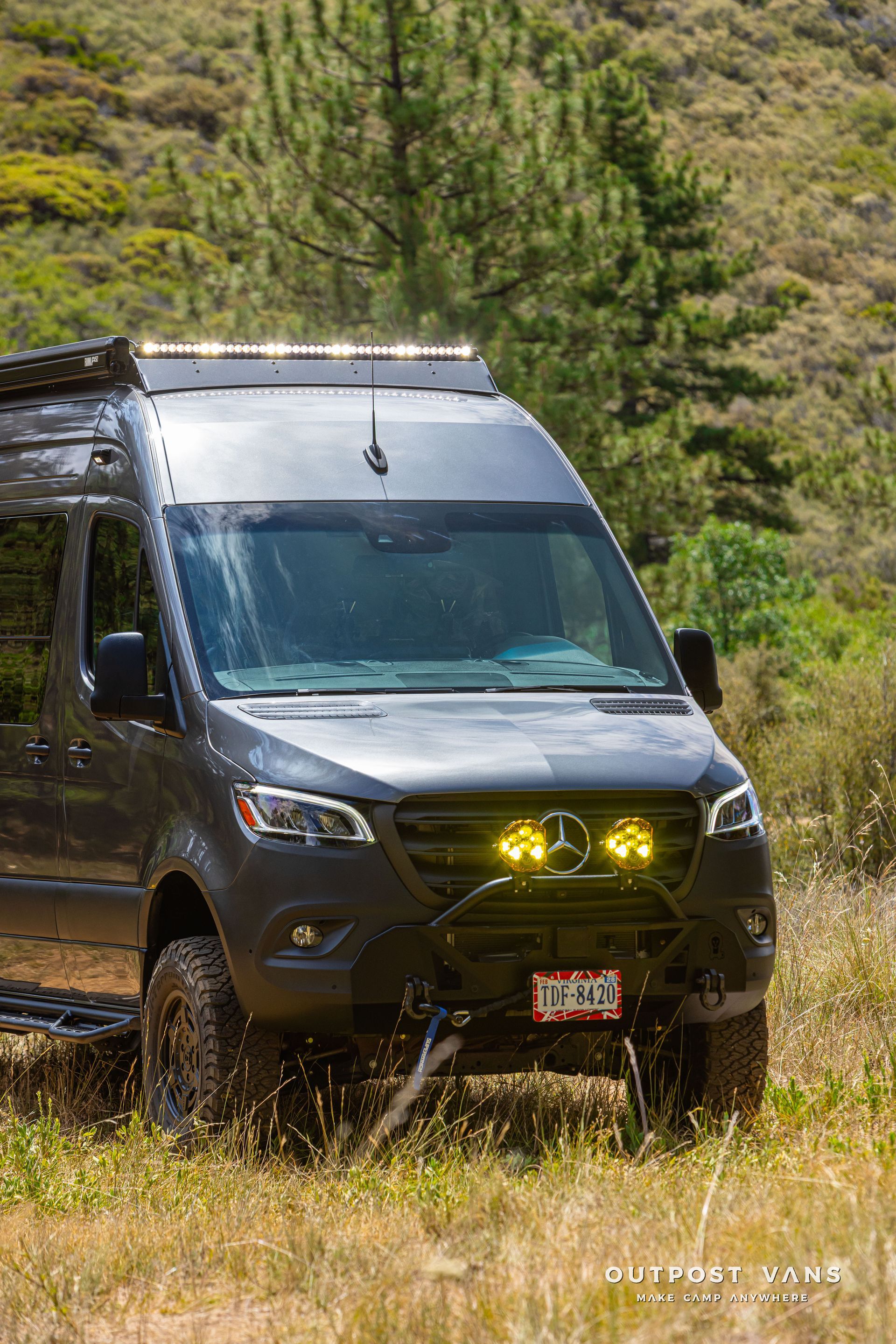 A mercedes sprinter van is parked in a grassy field. Outpost vans Sprinter 170 AWD.