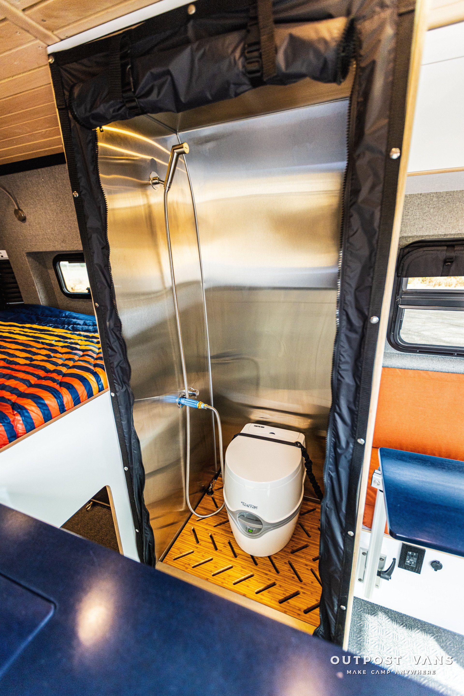 a bathroom in a camper van with a toilet and shower .