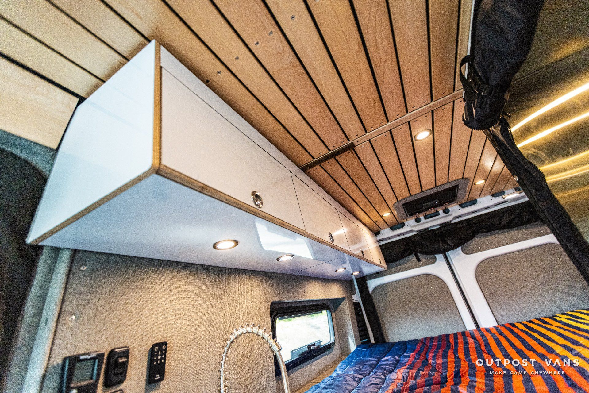 A van with a wooden ceiling and a bed in the back.