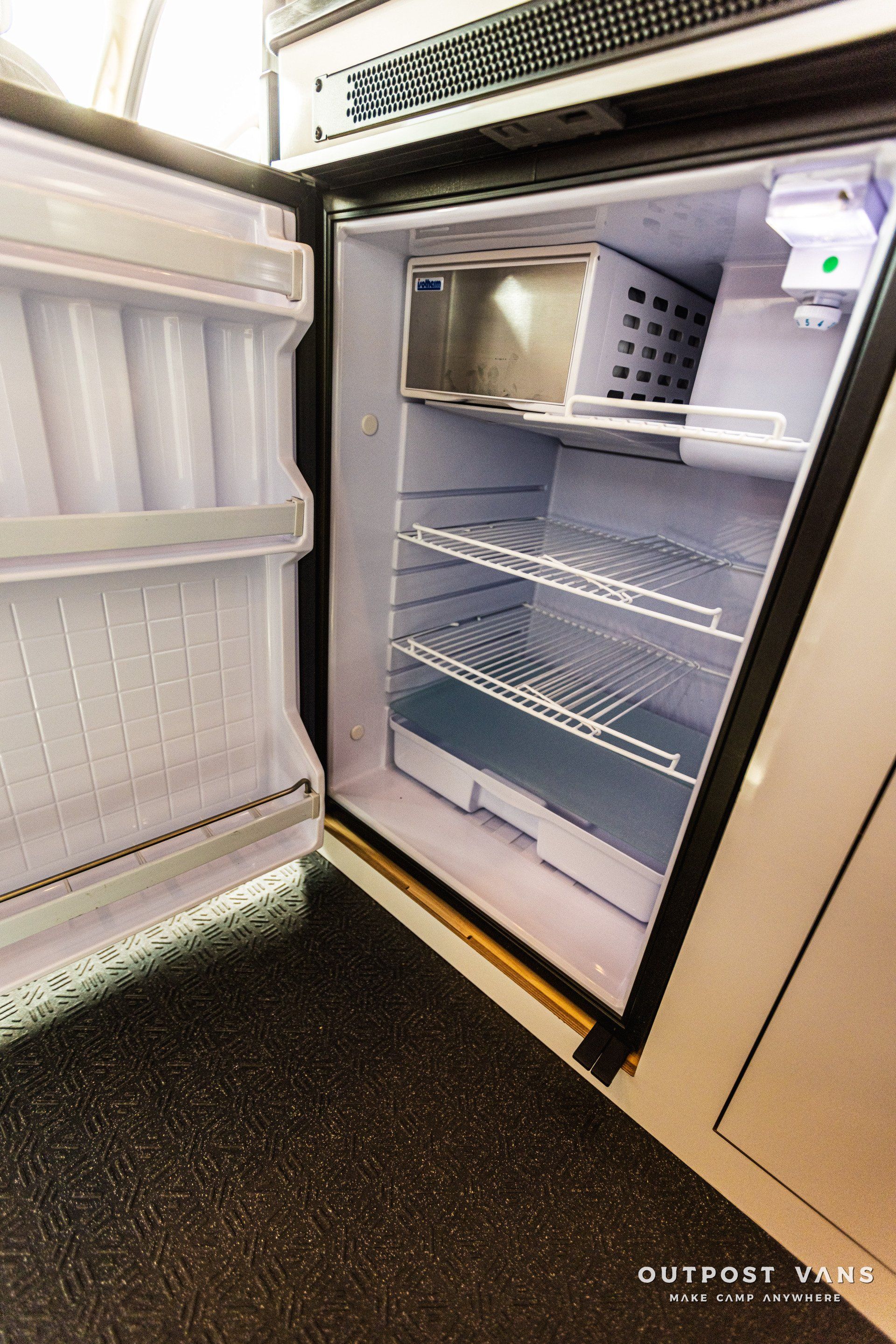 An empty refrigerator with the door open in a kitchen.