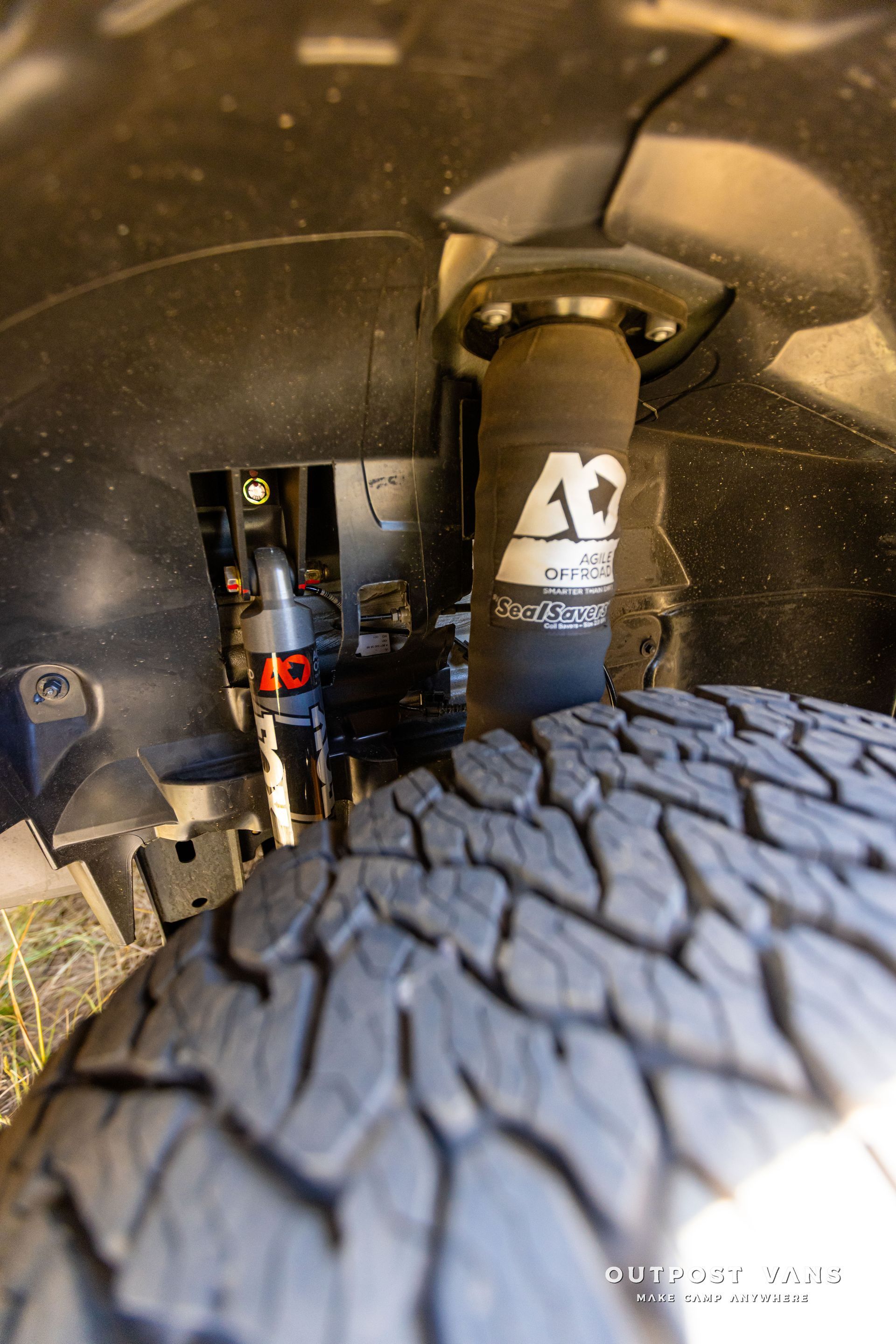 A close up of a shock absorber and a tire on a truck. Outpost vans Sprinter 170 AWD.