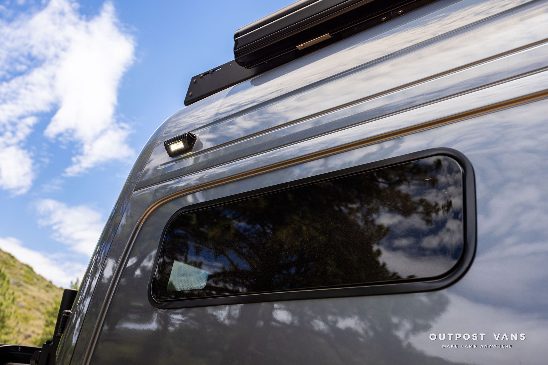 A close up of a van with a roof rack and a window. Outpost vans Sprinter 170 AWD.