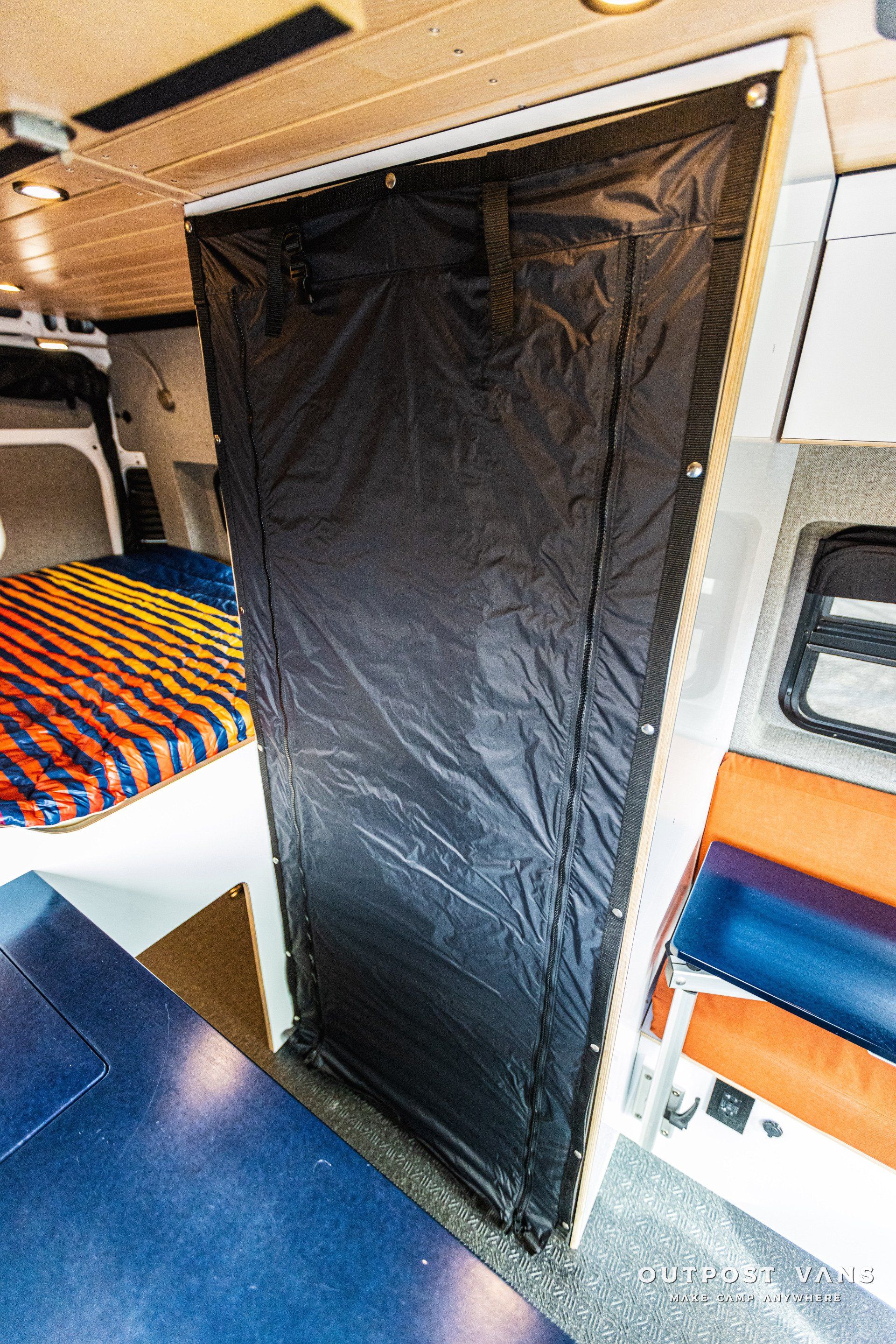 A black door in a van with a bed in the background.