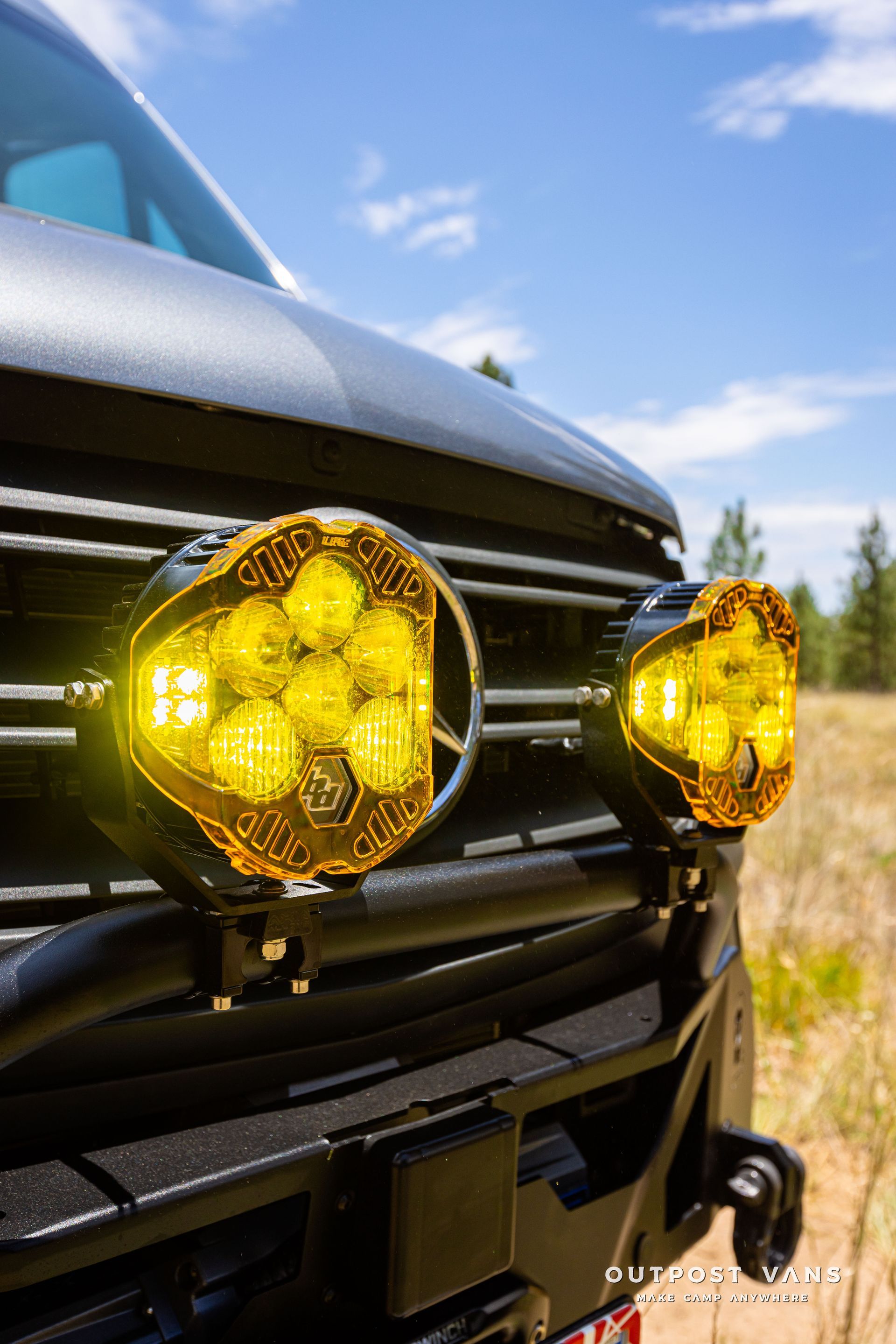 A close up of the front of a truck with yellow lights on it. Outpost vans Sprinter 170 AWD.