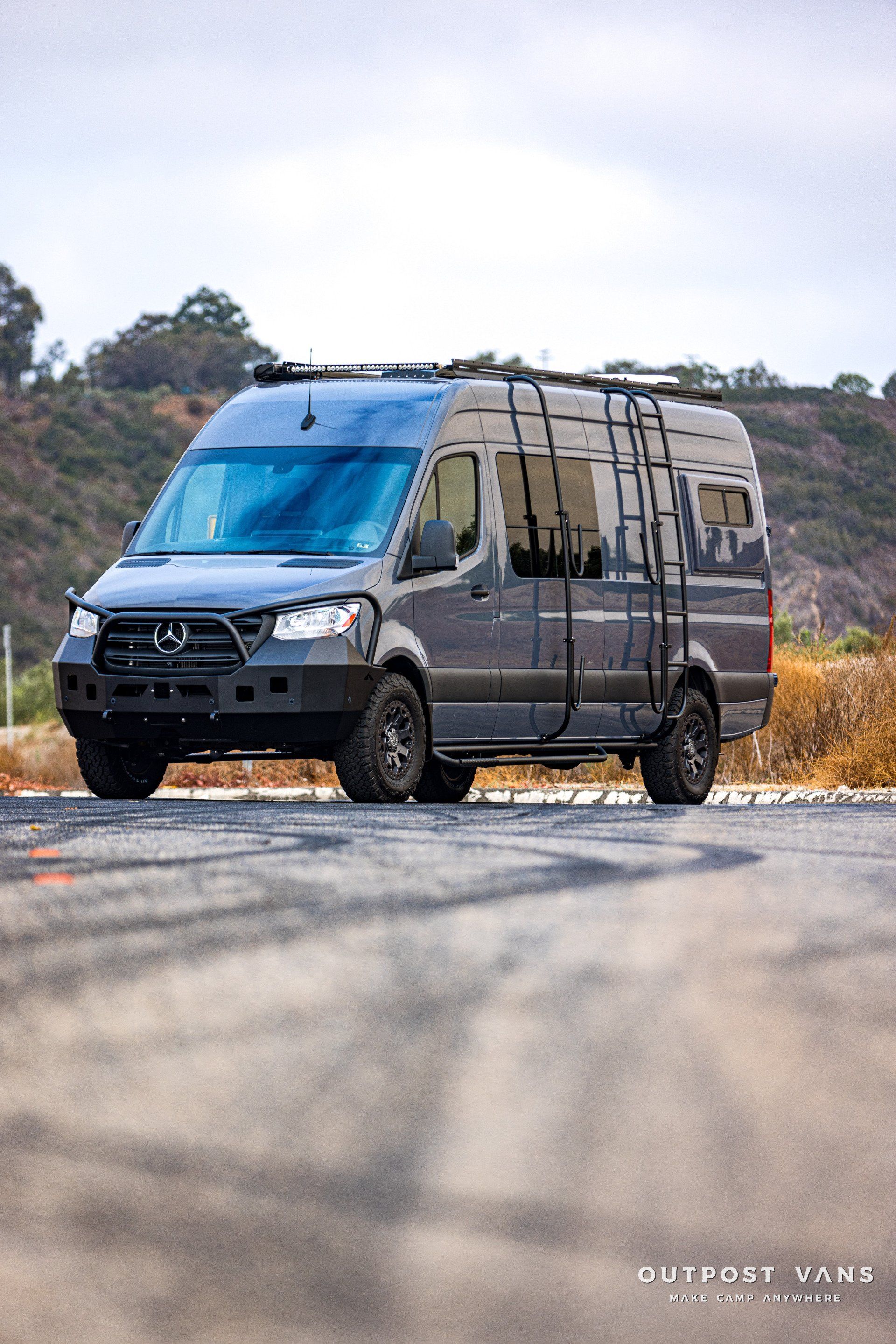 A van with a ladder on the roof is parked on the side of a road.