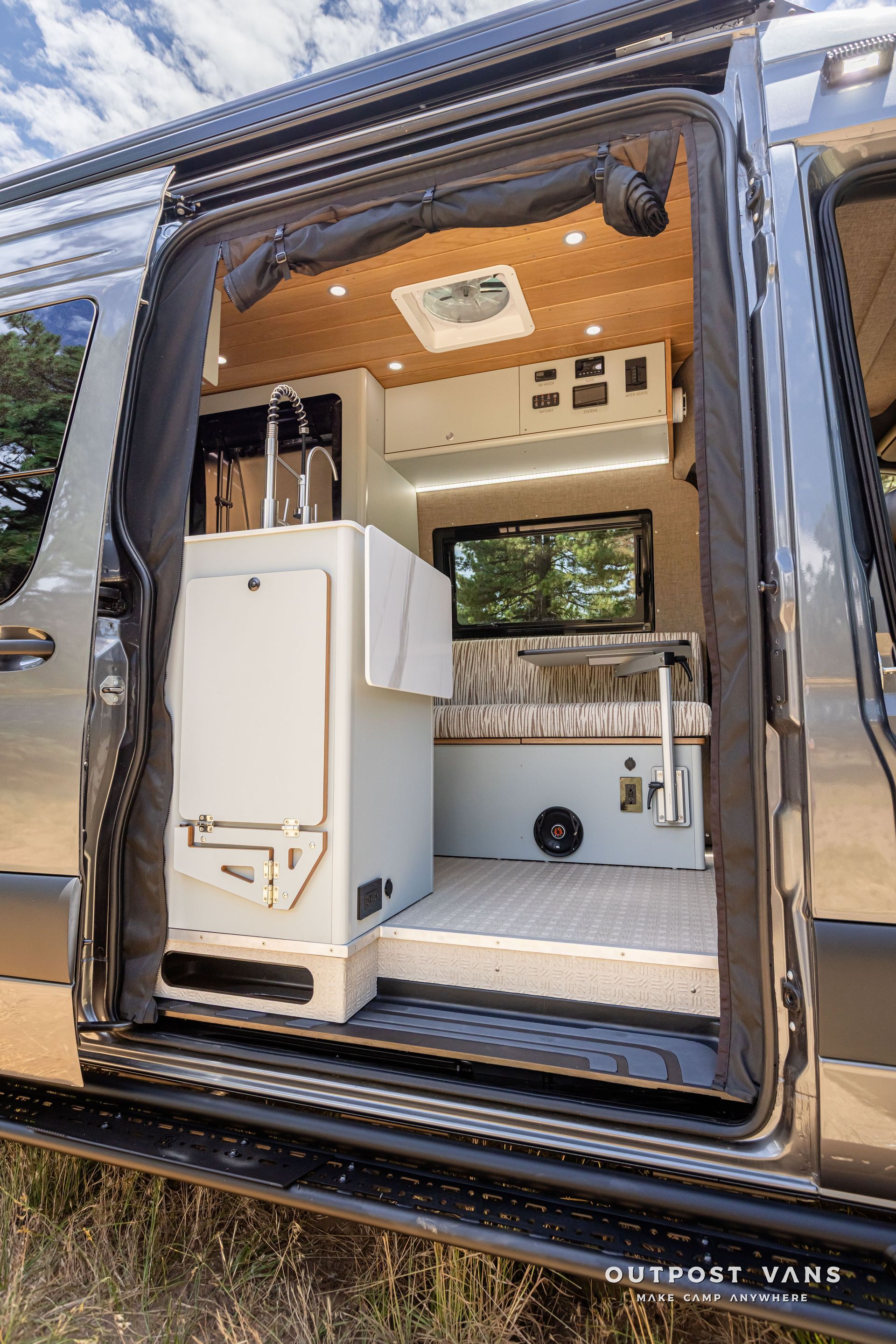 The inside of a camper van with the door open. Outpost vans Sprinter 170 AWD.