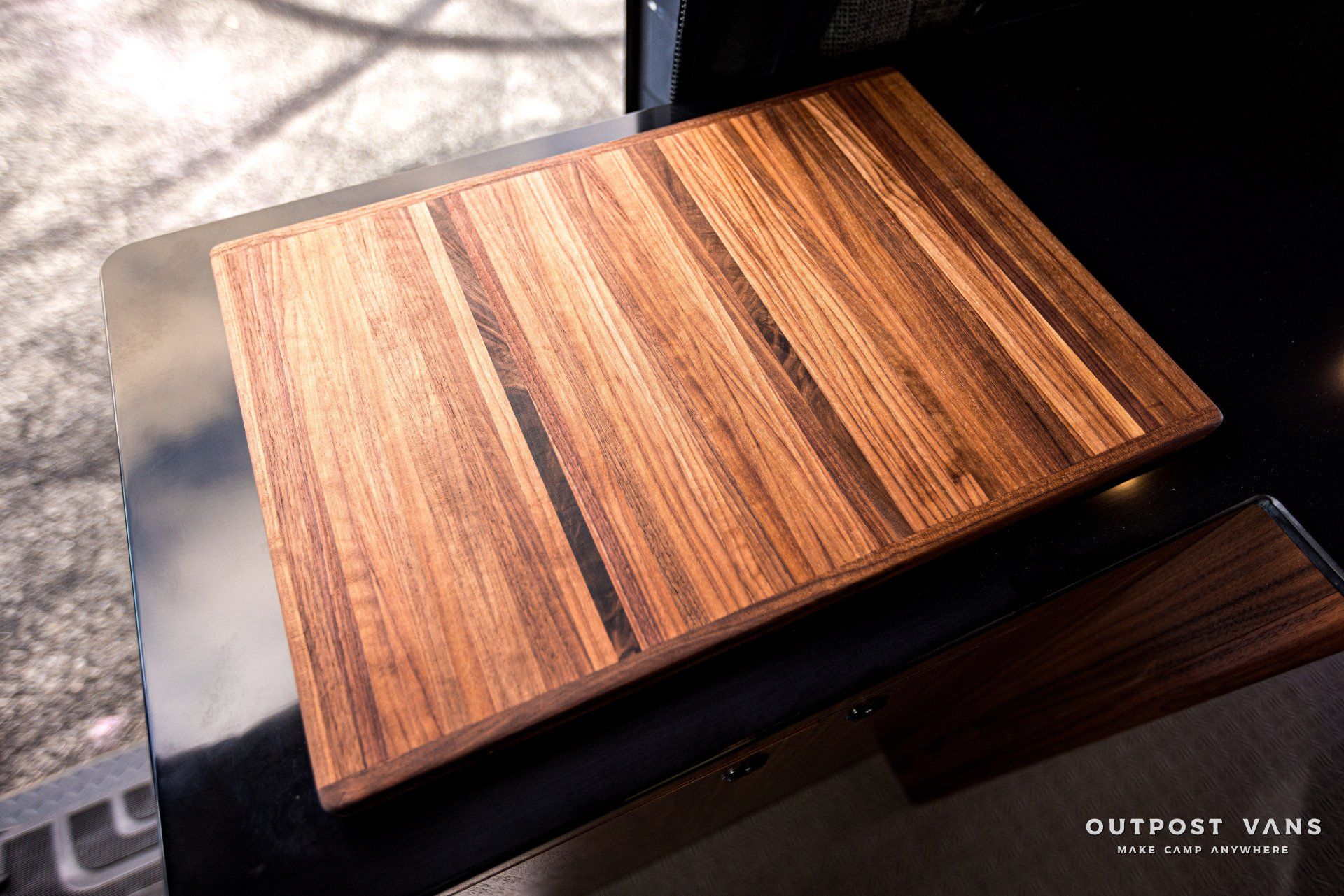 A wooden cutting board is sitting on top of a black table.