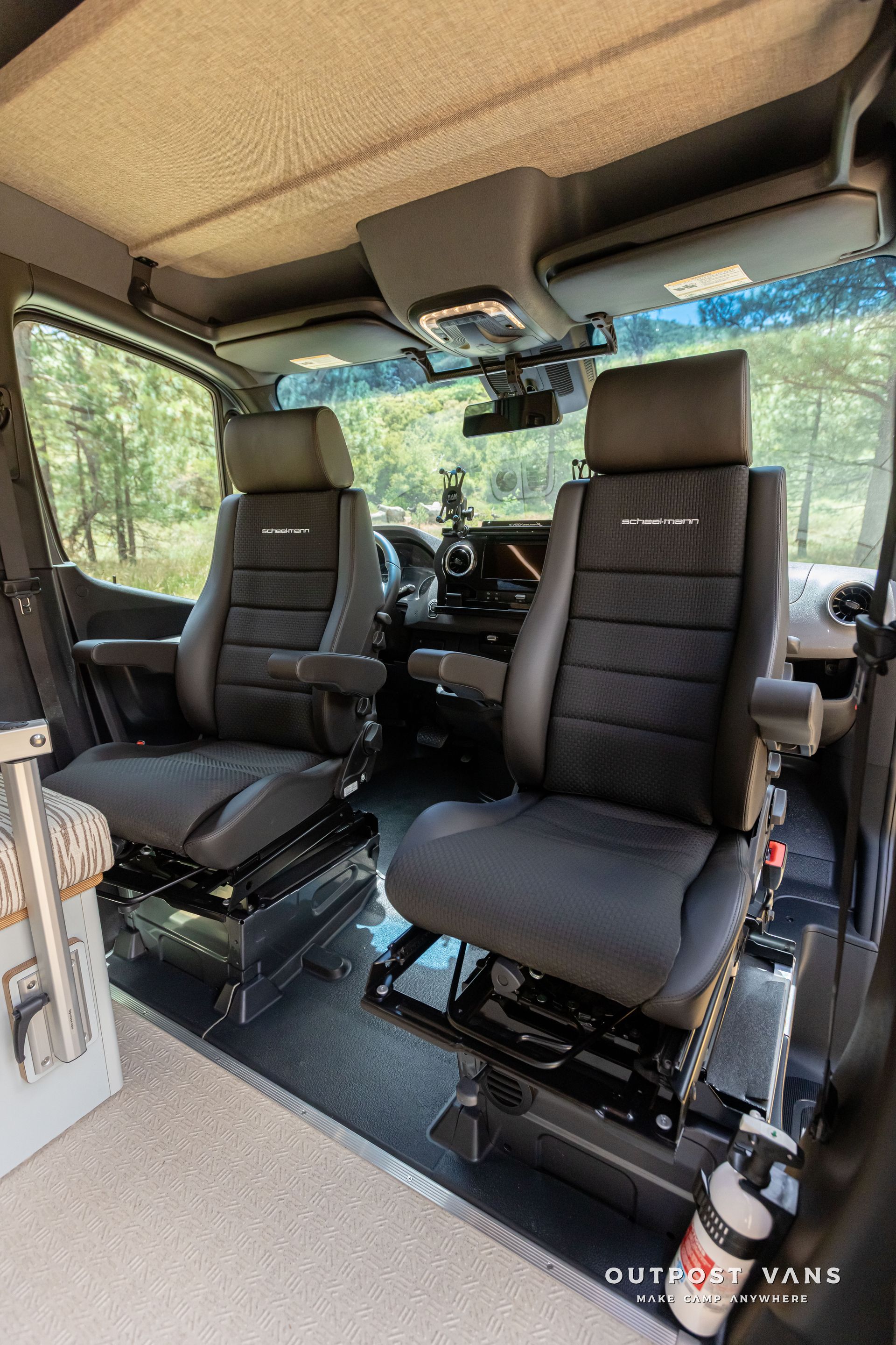 The interior of a van with two seats and a fire extinguisher. Outpost vans Sprinter 170 AWD.