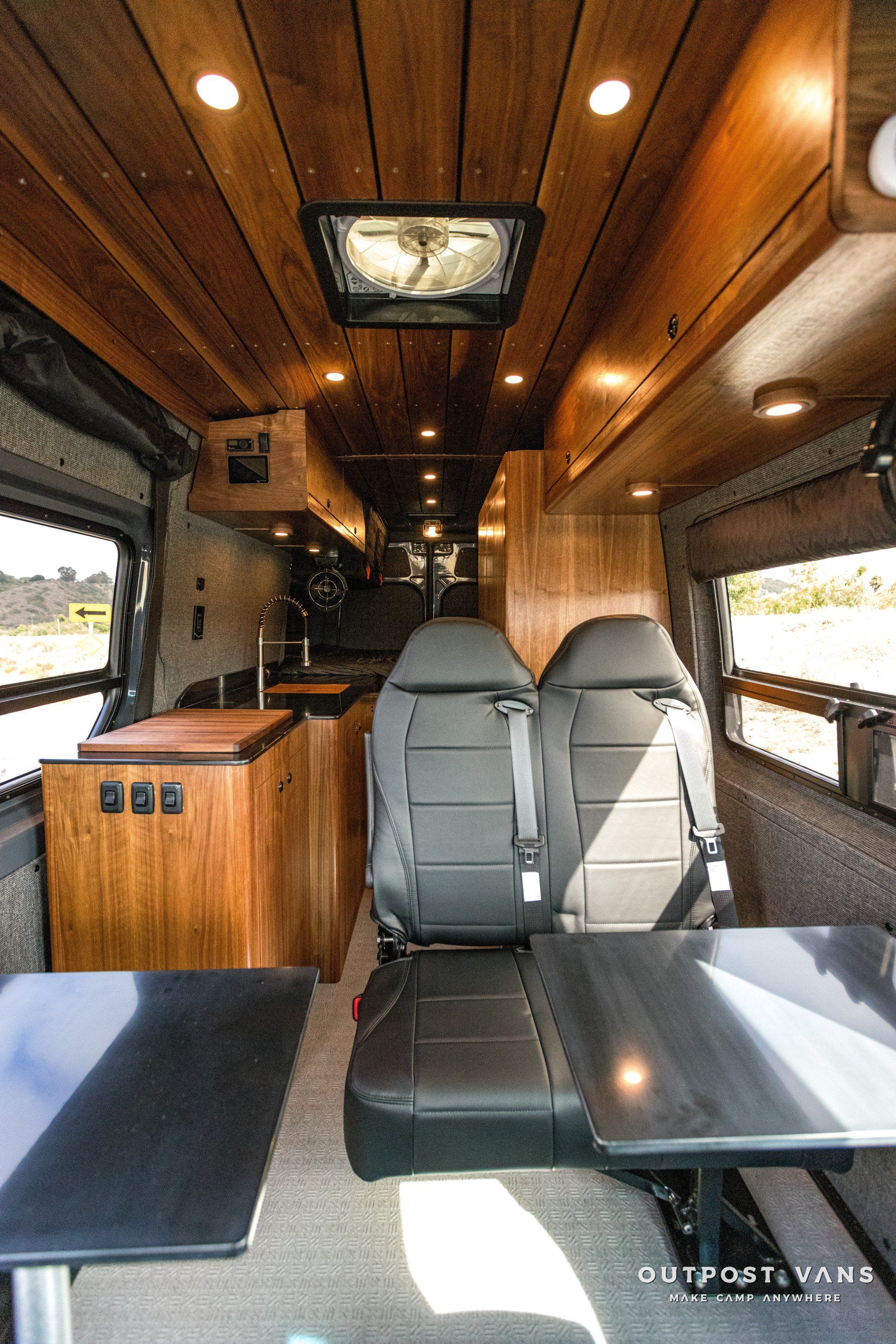 The inside of a camper van with tables and chairs.