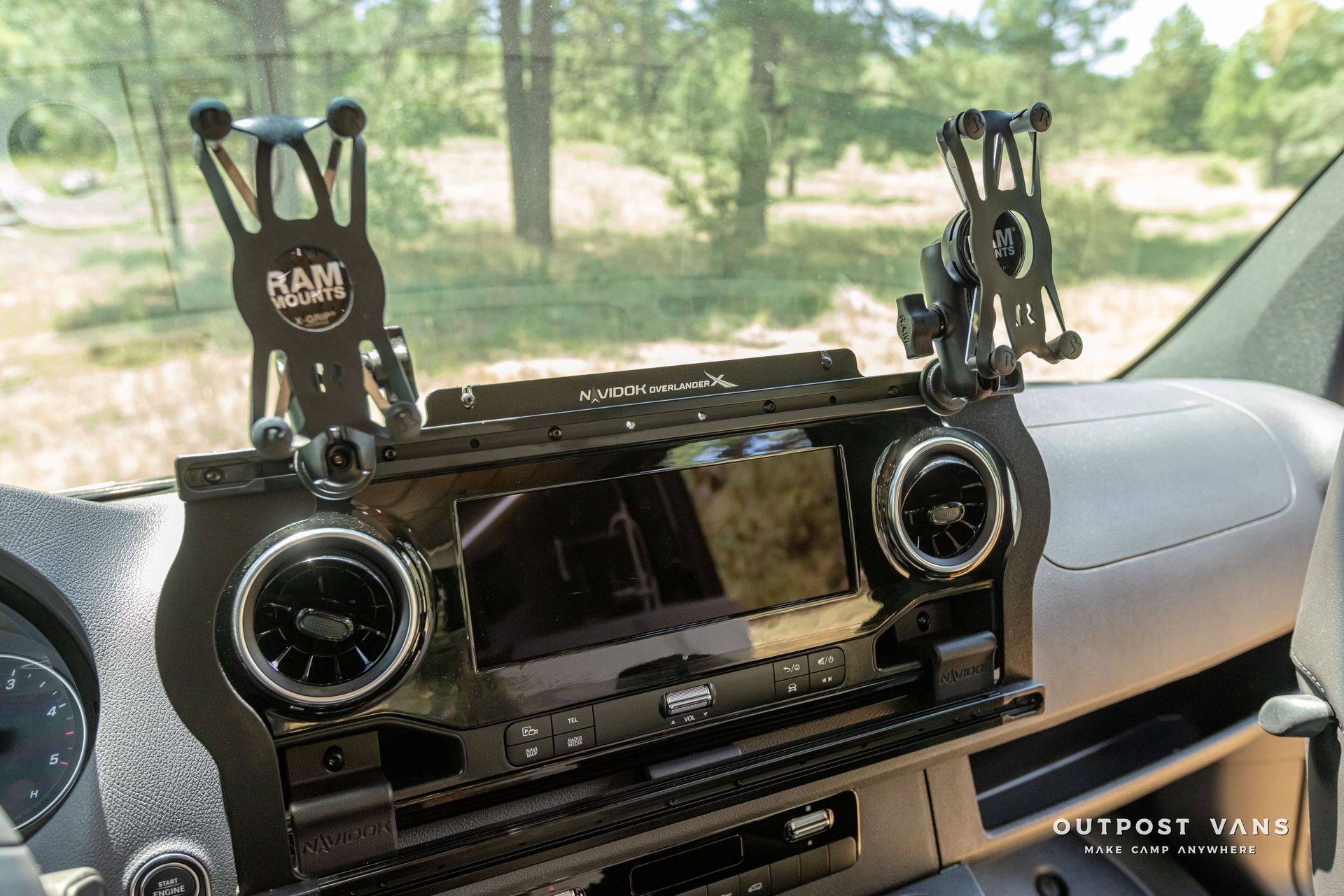 A phone holder is sitting on the dashboard of a car. Outpost vans Sprinter 170 AWD.