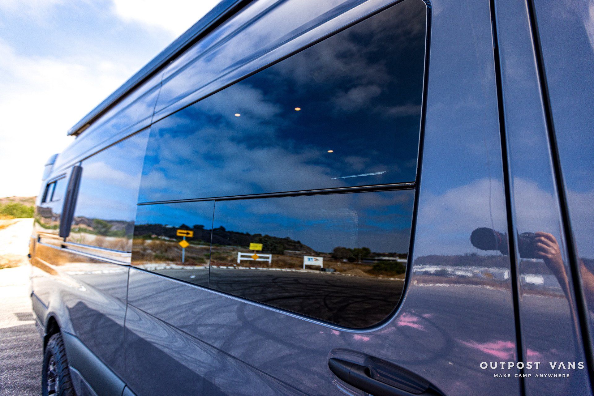 A van with a large window is parked on the side of the road.