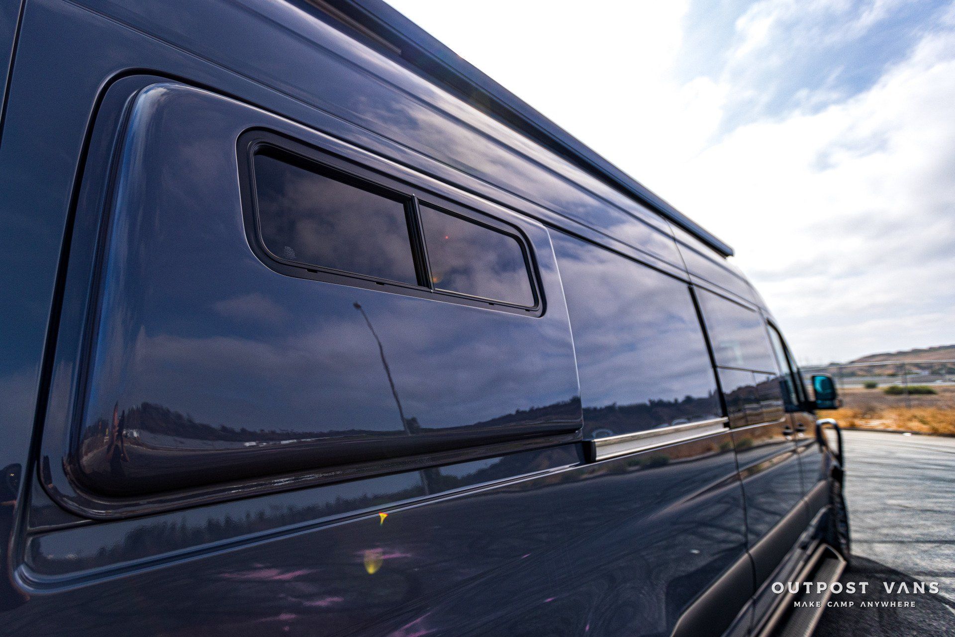 A black van is parked next to a body of water.