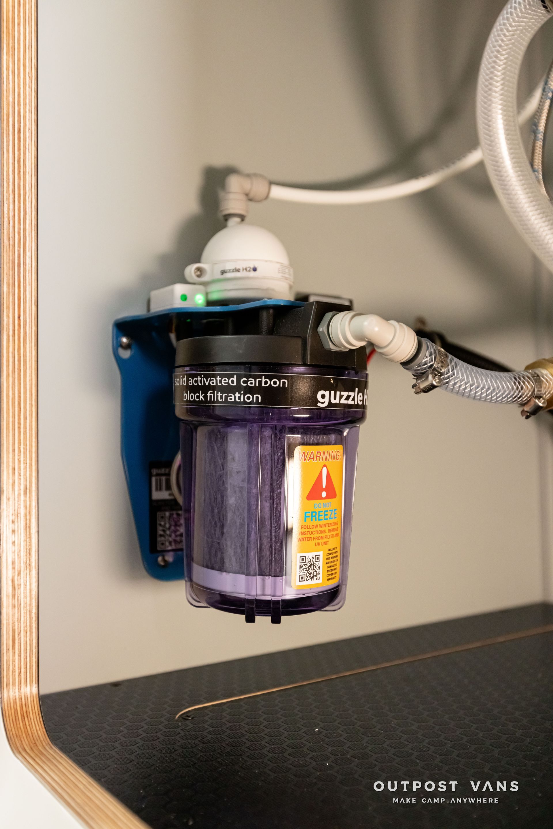 guzzle water filter is attached to a wall under a sink. Outpost vans Sprinter 170 AWD.