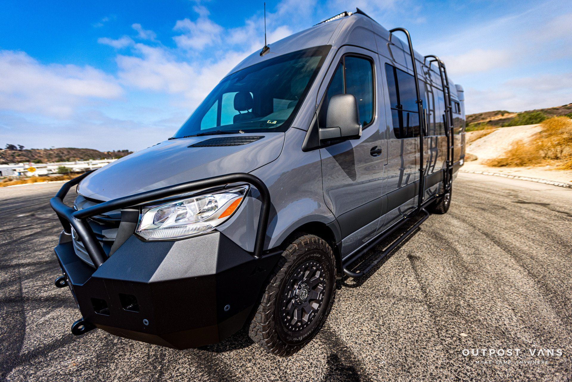 A silver van is parked on the side of a dirt road.