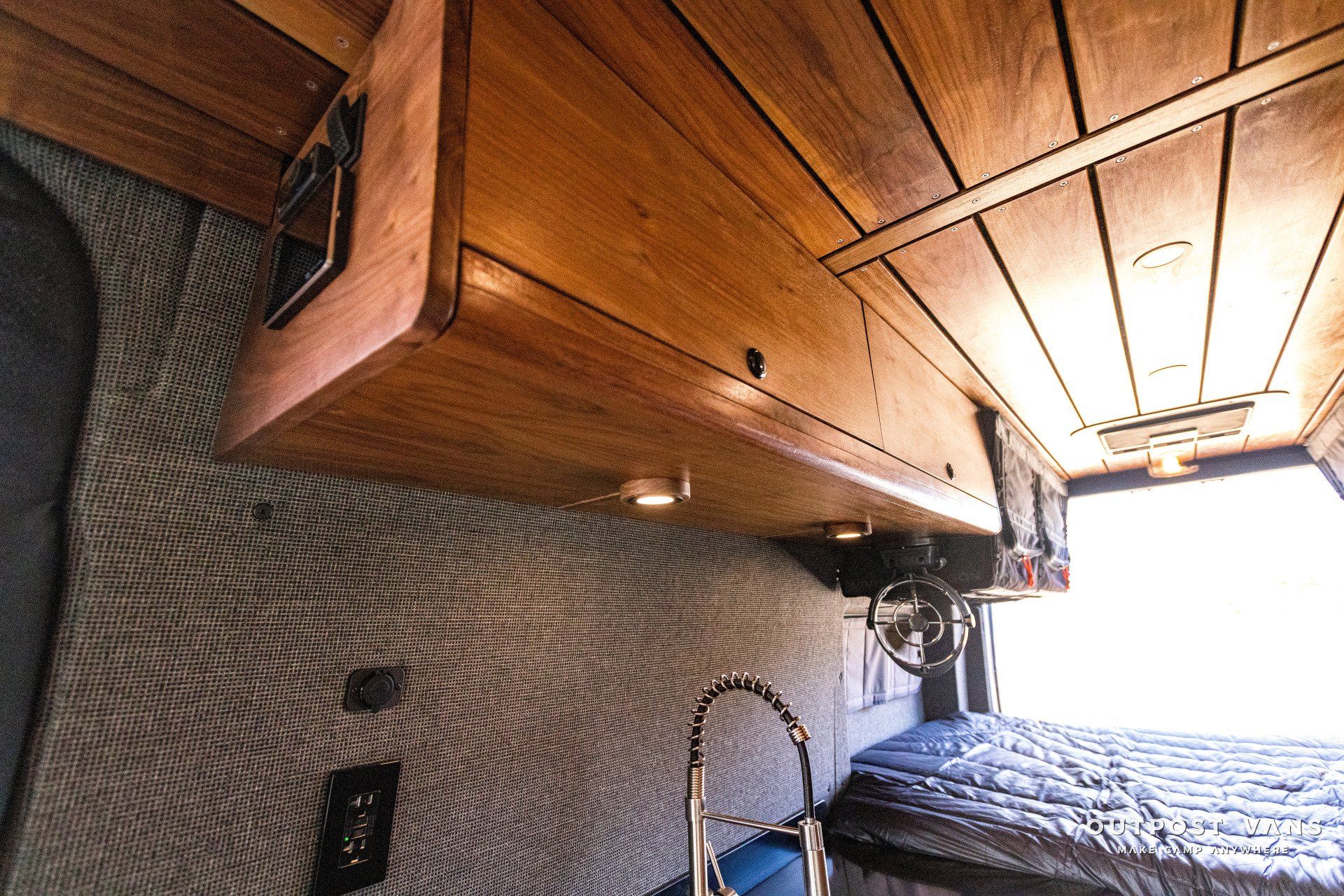 A kitchen in a van with wooden cabinets and a sink.