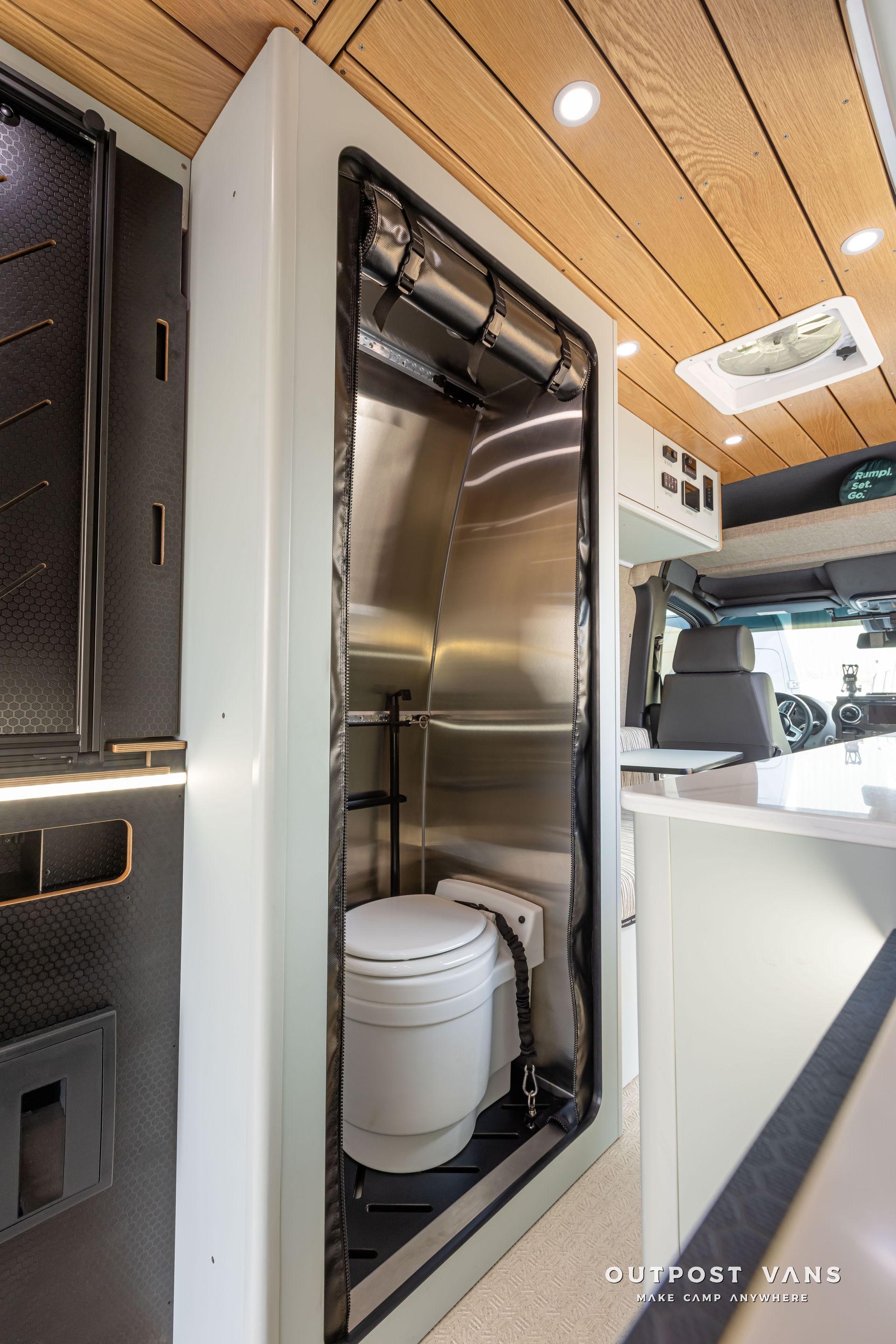 A bathroom in a van with a toilet and a sink. Outpost vans Sprinter 170 AWD.