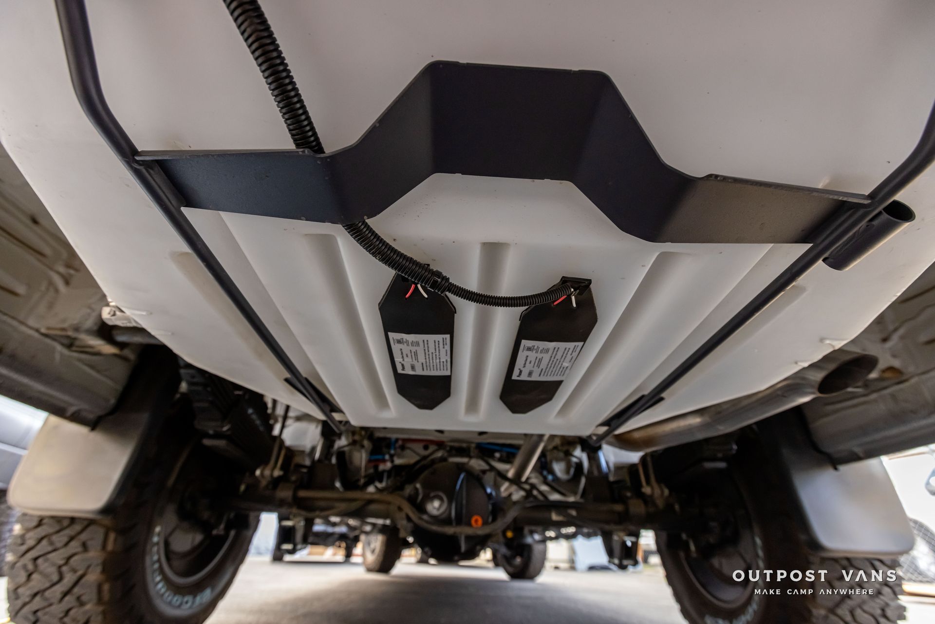 The bottom of a white truck with a tank underneath it. Outpost vans Sprinter 170 AWD.