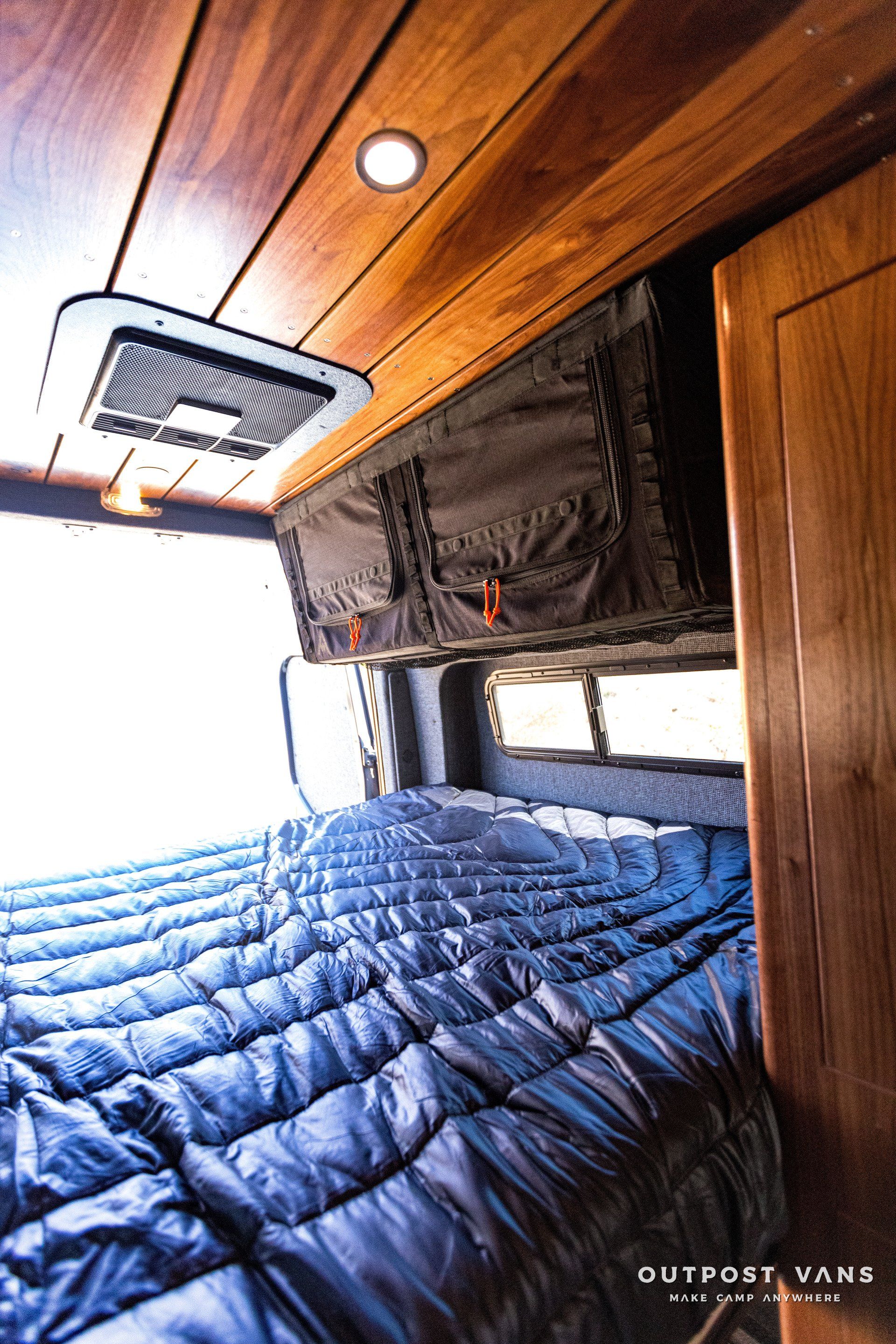 The inside of a van with a bed and a ceiling fan.