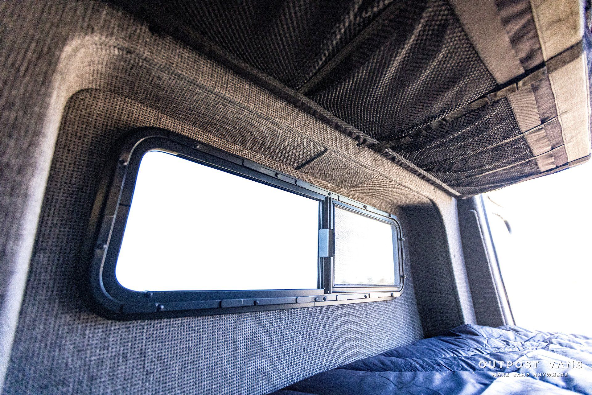 The inside of a van with a bed and a window.
