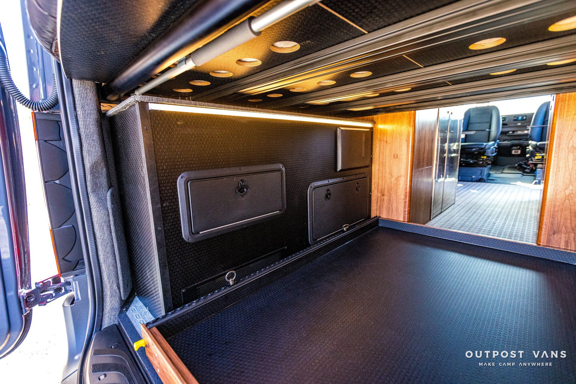 The inside of a van with a bed and chairs.