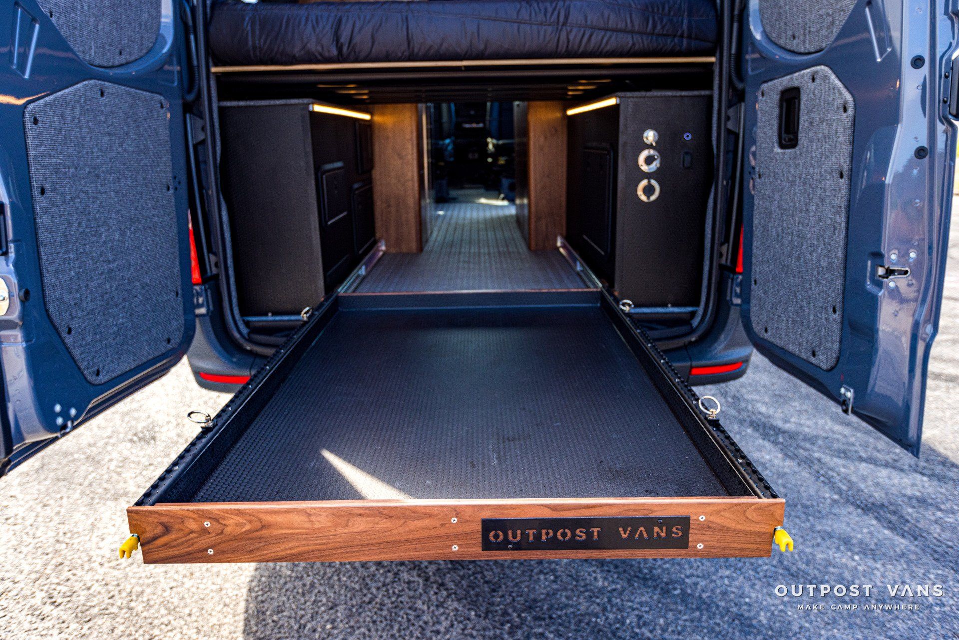 The back of a van with the door open and a wooden drawer.