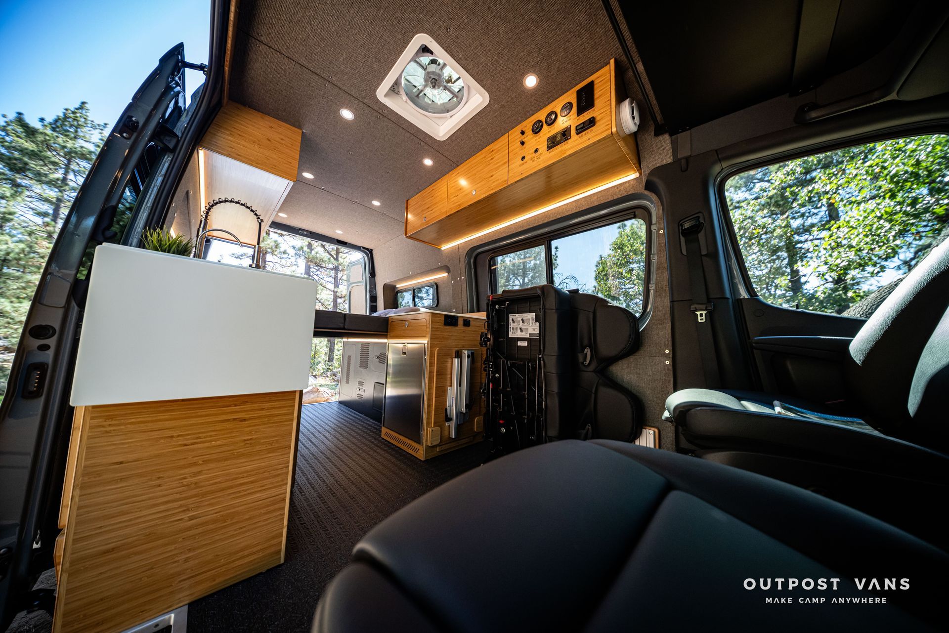 Sprinter Inside a custom van, featuring wood accents, dark flooring, and a modern interior.