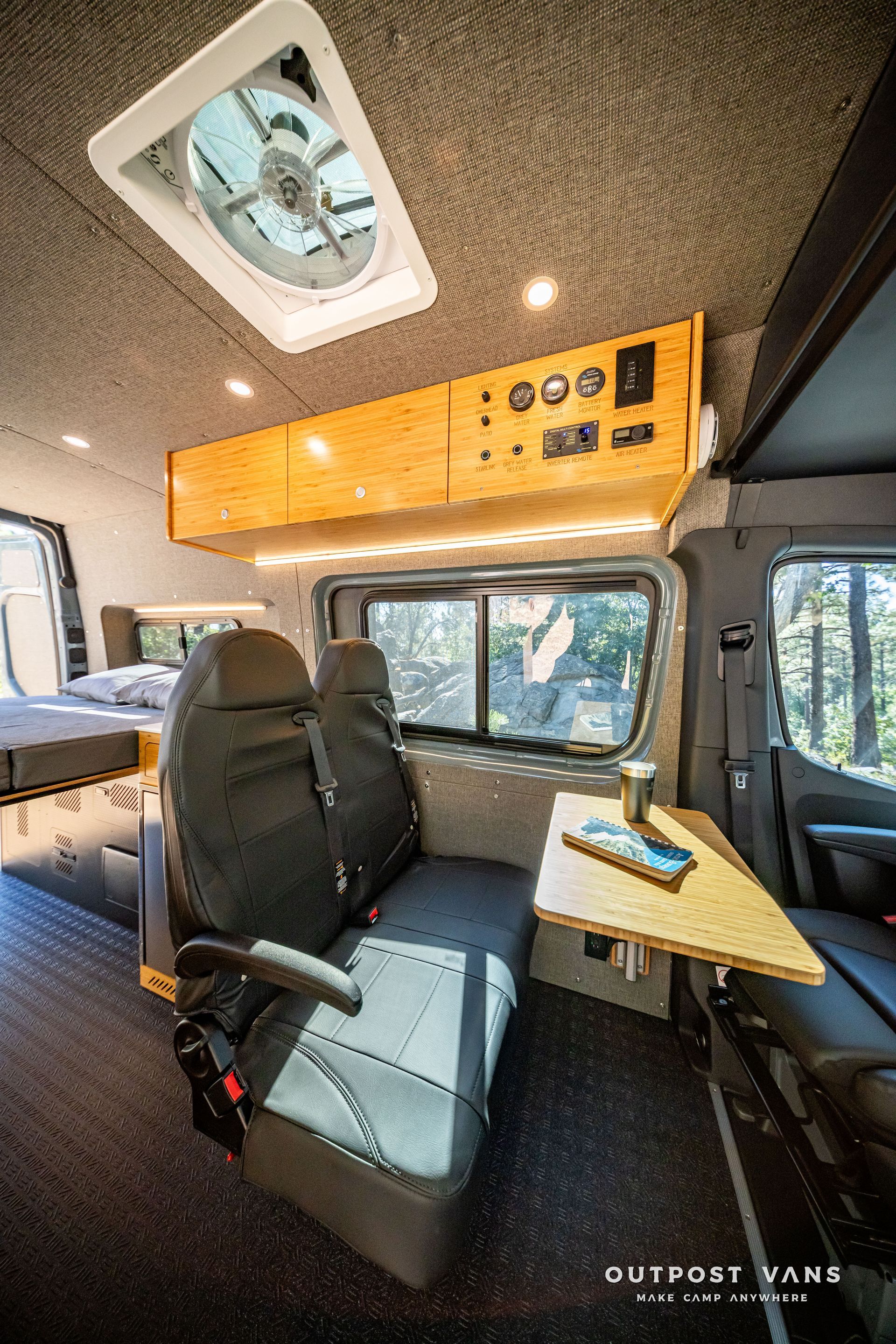 Sprinter Interior of a camper van, with custom wood features, seating, and a fan in the ceiling.