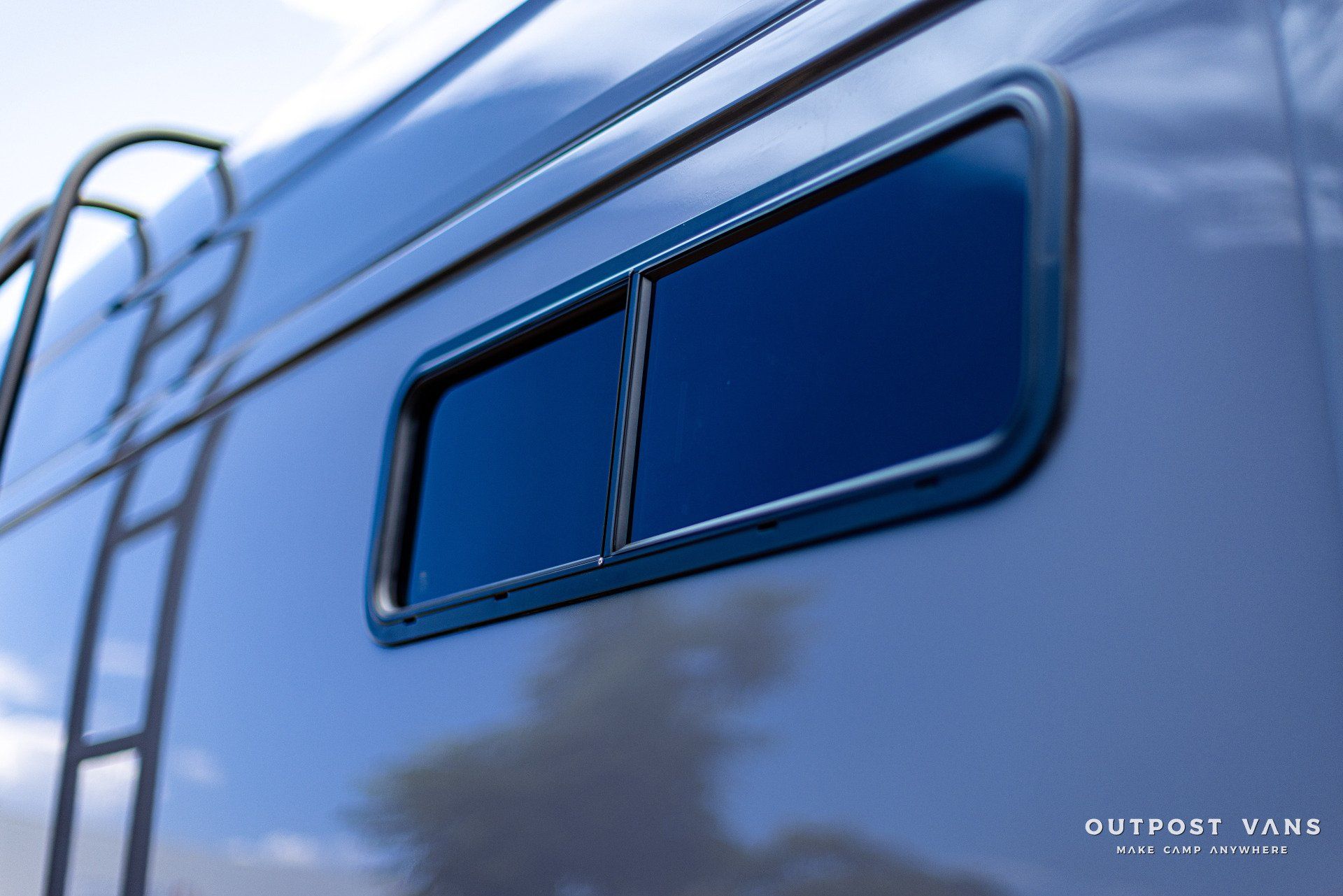 A blue van with a window and a ladder on the side.