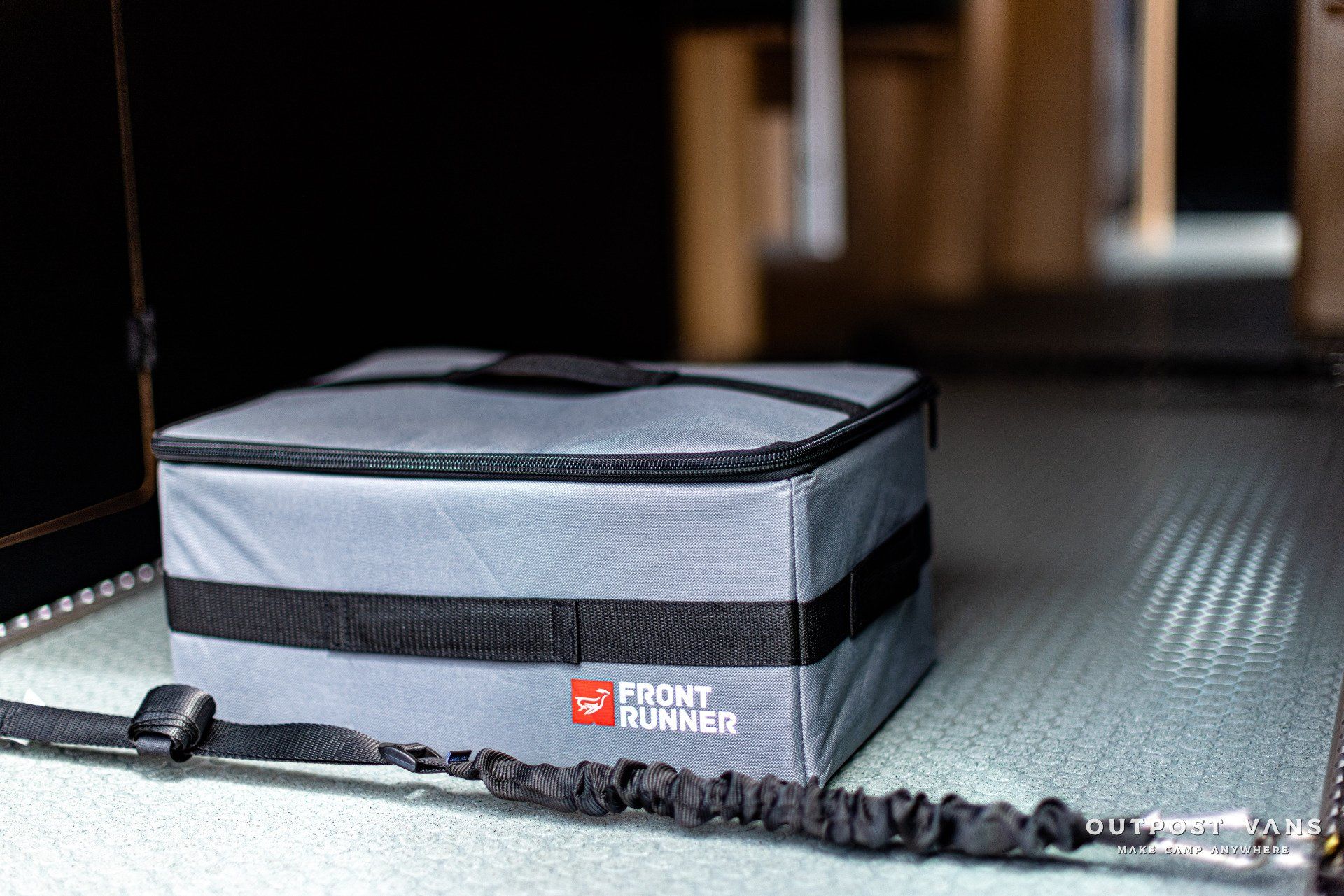 a cooler bag with a strap is sitting on the floor .