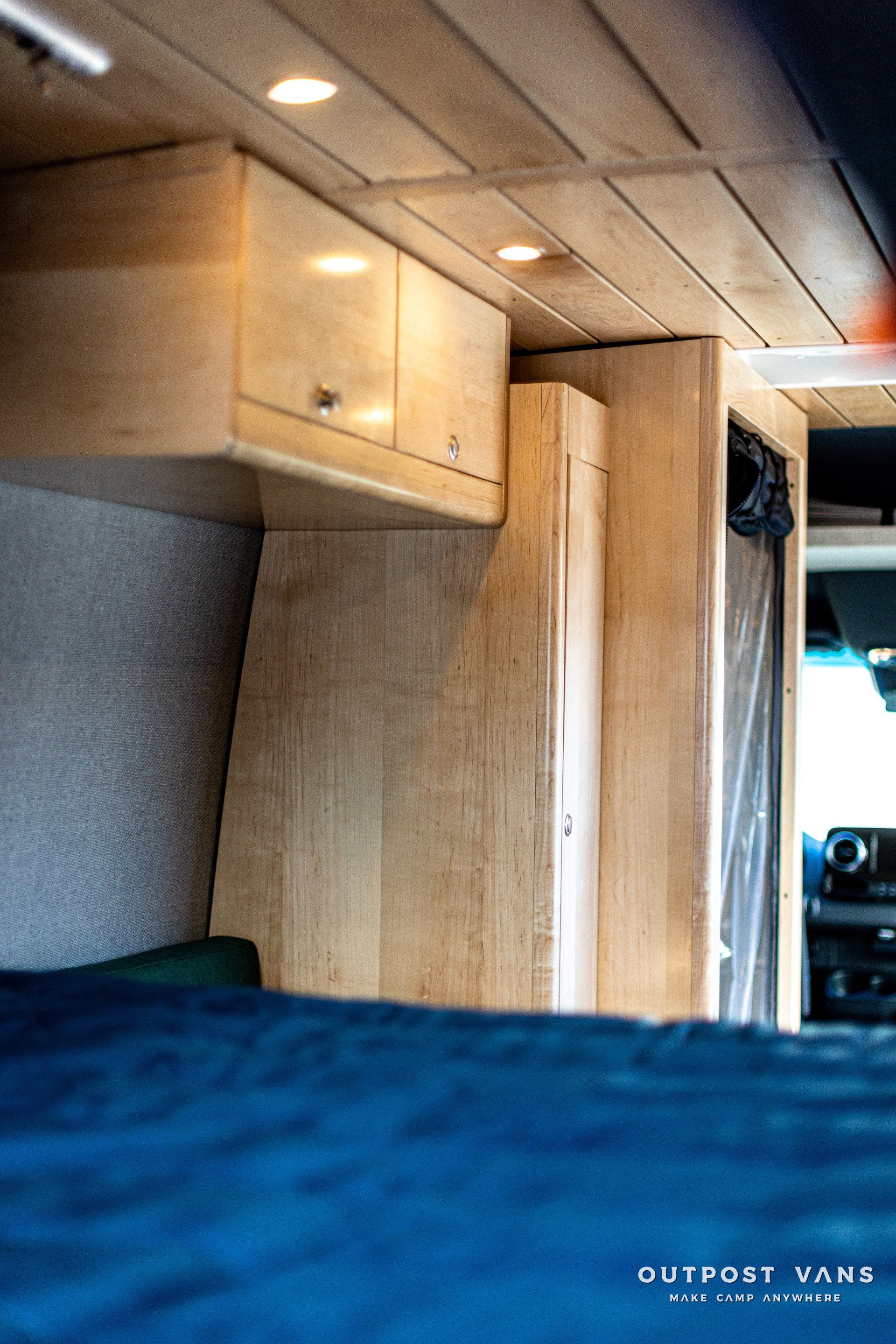 A camper van with a bed and cabinets on the ceiling