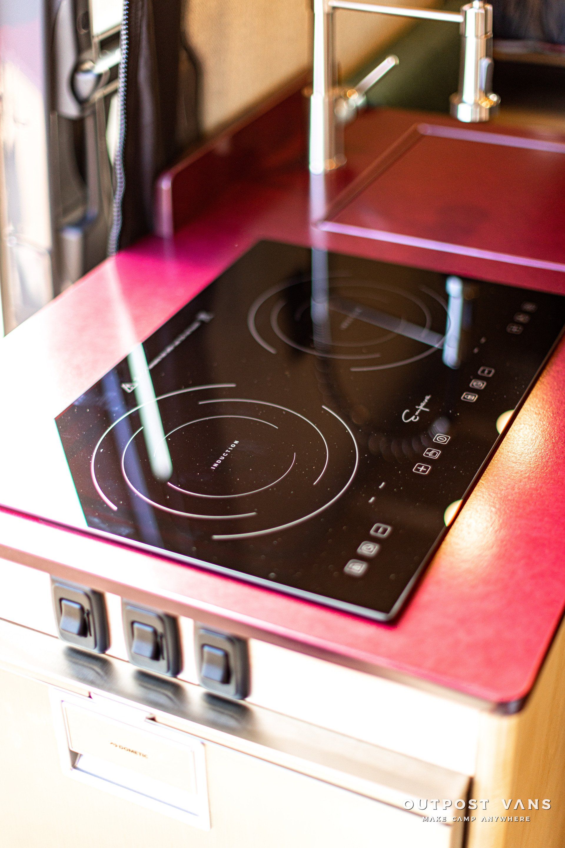 A stove top oven is sitting on top of a red counter top.