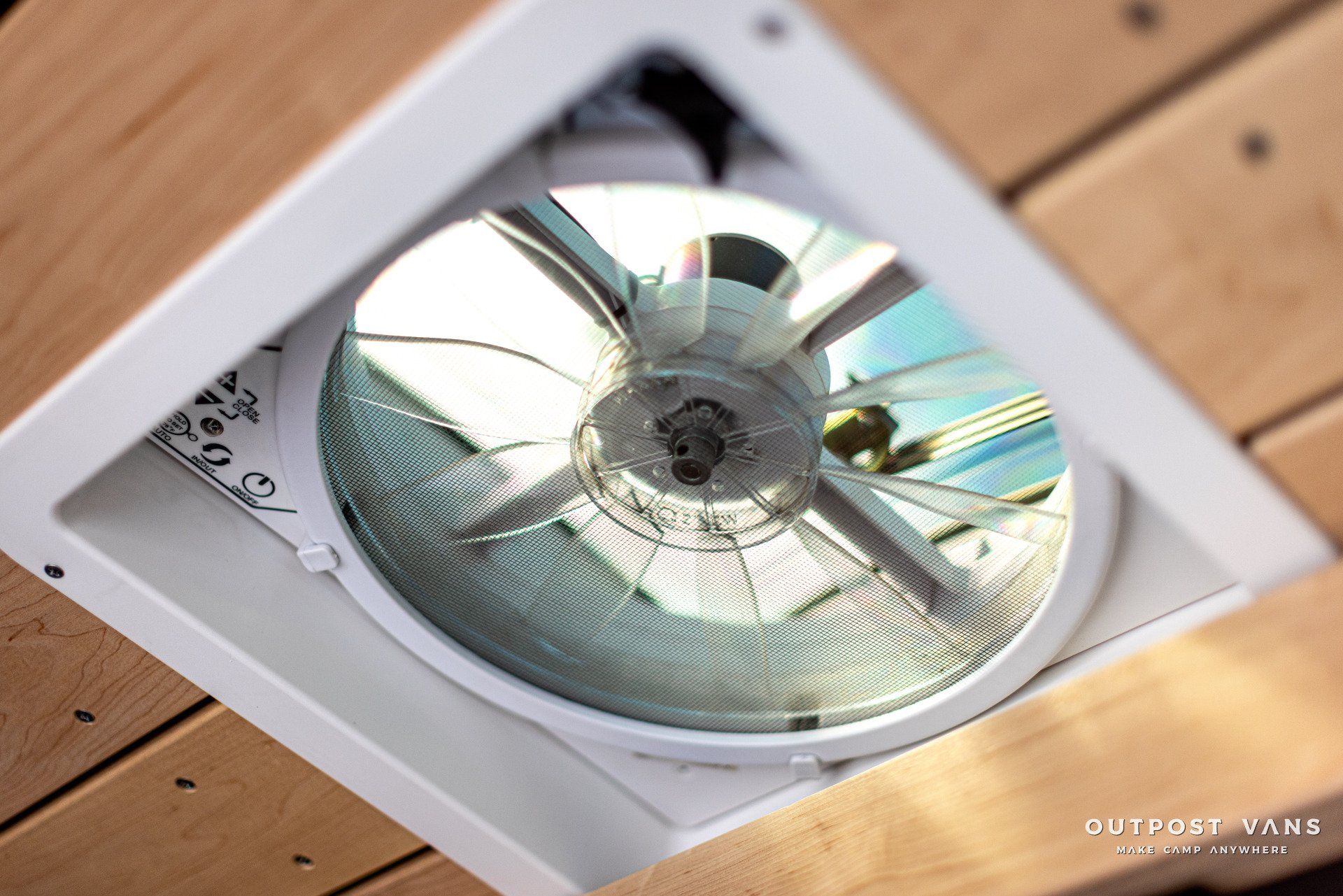 A close up of a fan on a wooden ceiling