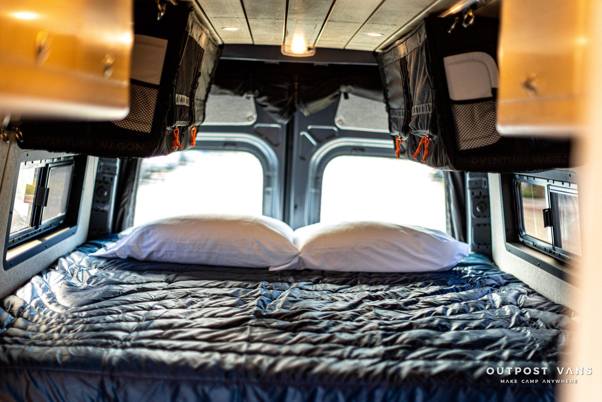 a bed in the back of a van with two pillows .