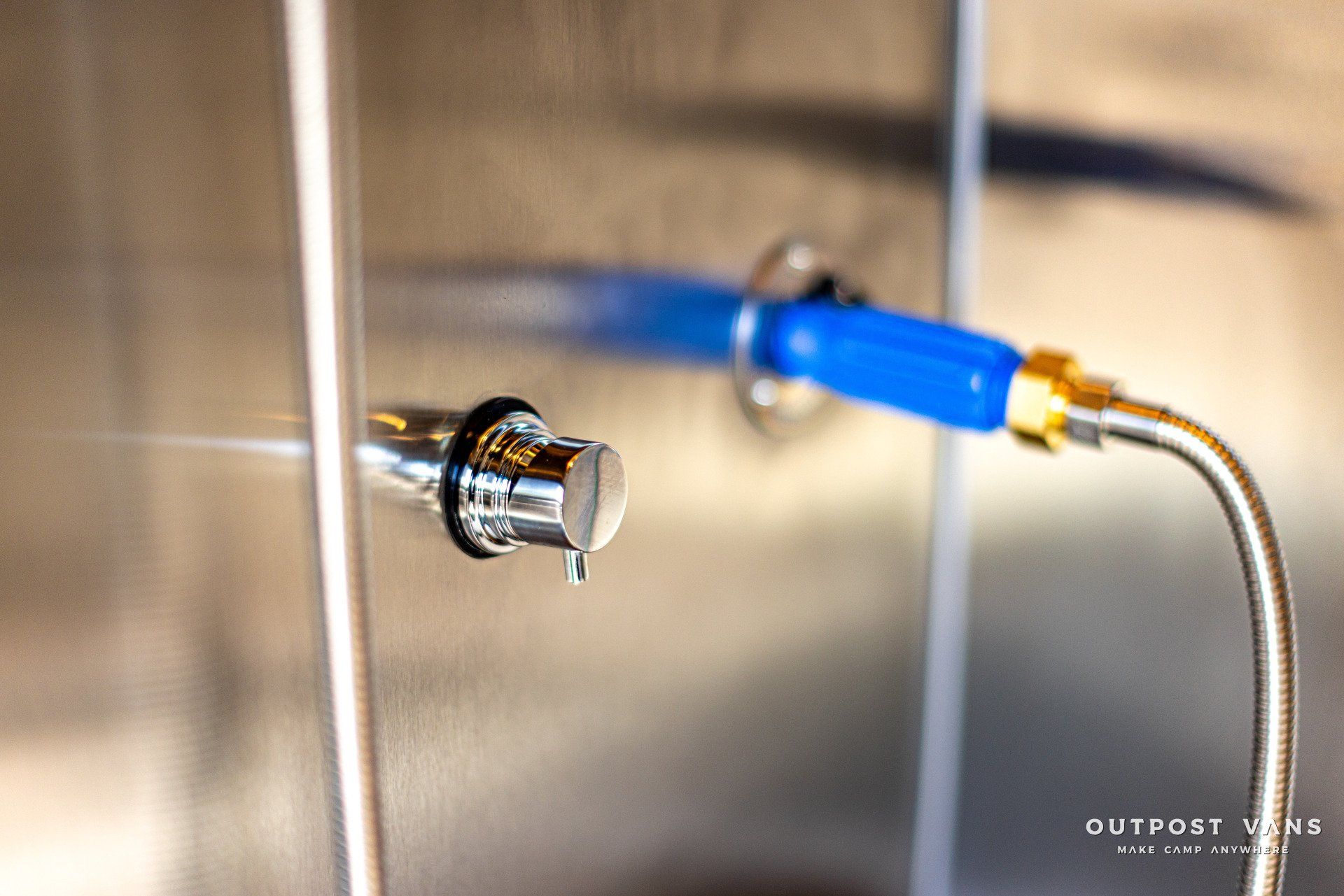 A close up of a faucet with a blue hose attached to it