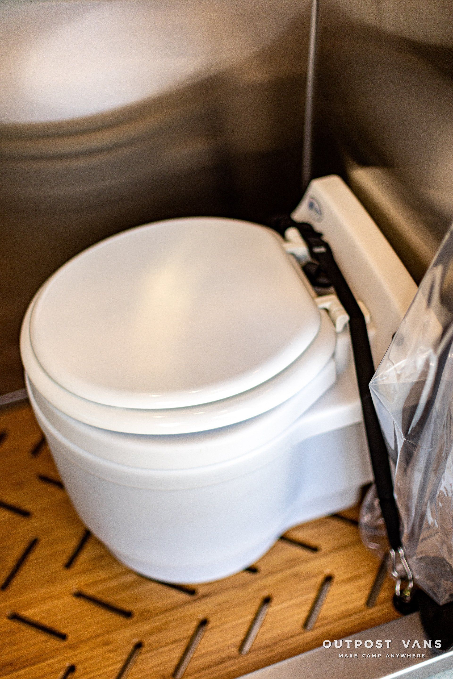 A white toilet is sitting on a wooden floor.