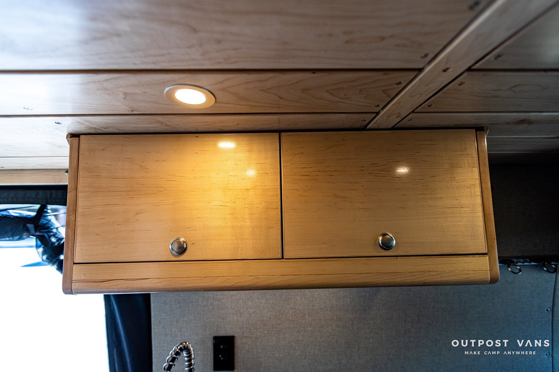 A wooden cabinet is hanging from the ceiling in a van