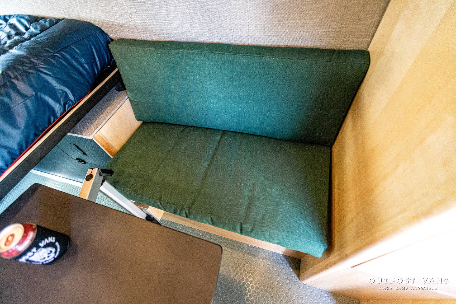 A green couch is sitting in a room next to a bed.