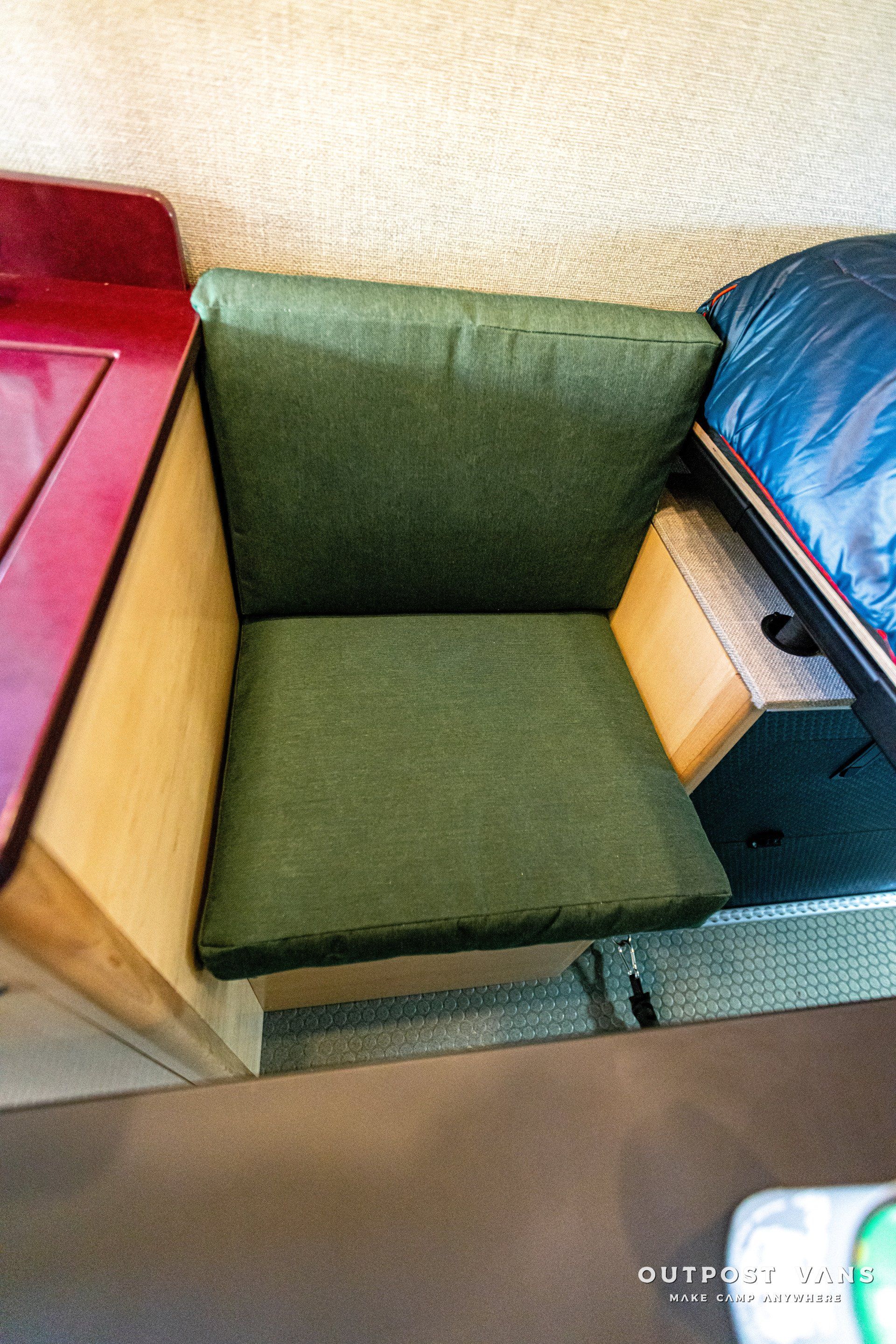A green chair is sitting in a room next to a bed.