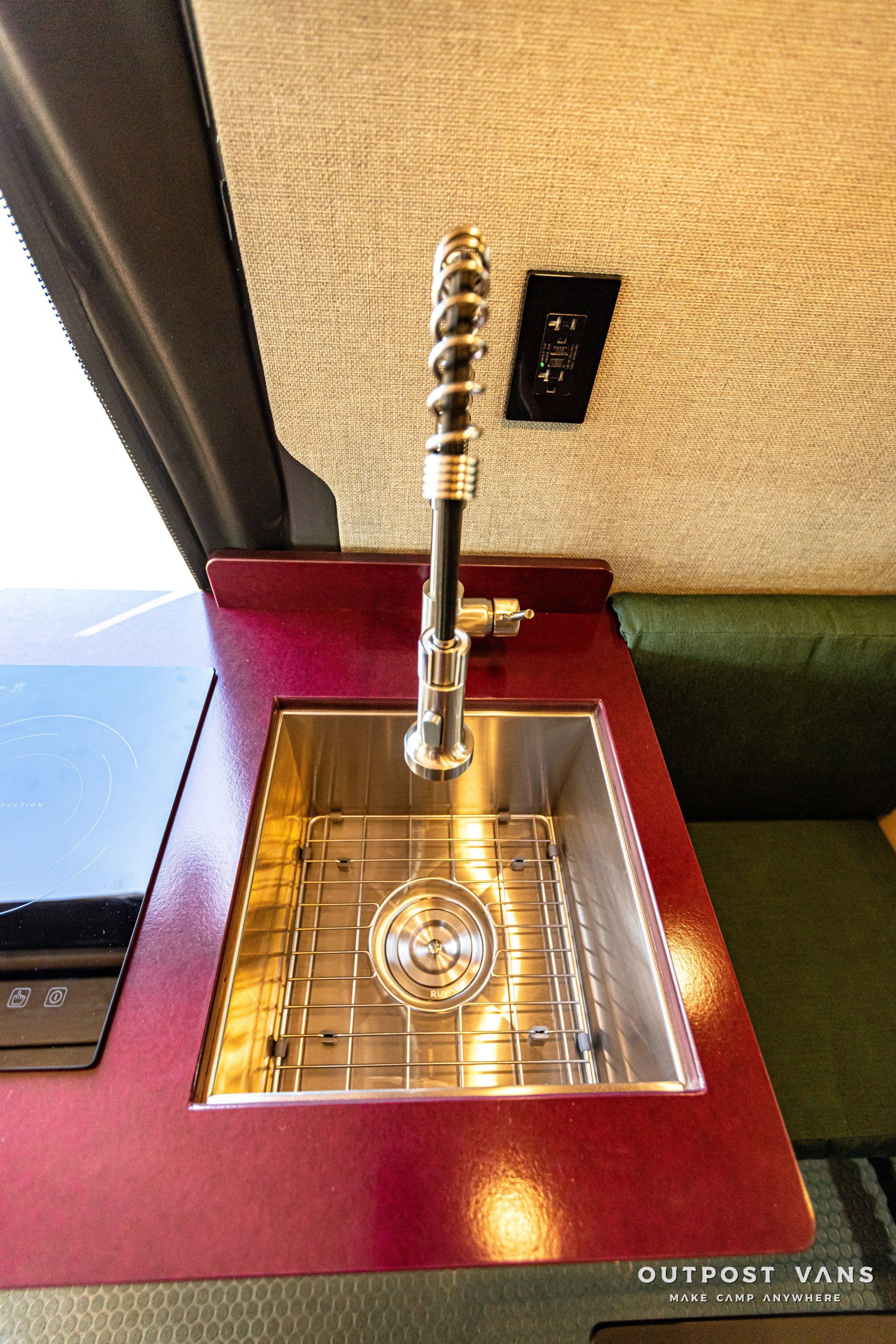 A stainless steel sink with a faucet on a red counter top.