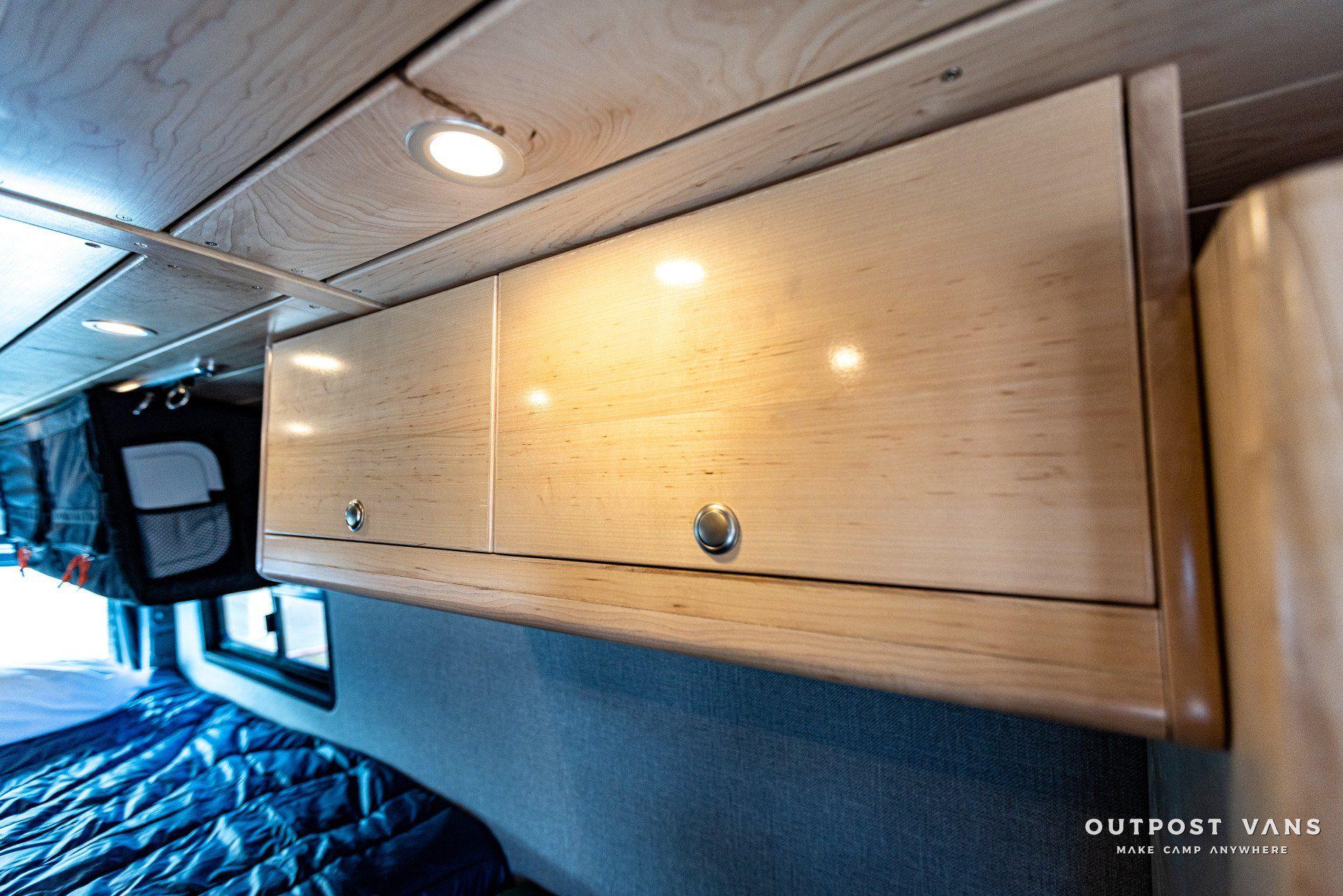 A wooden cabinet is hanging from the ceiling of a van.