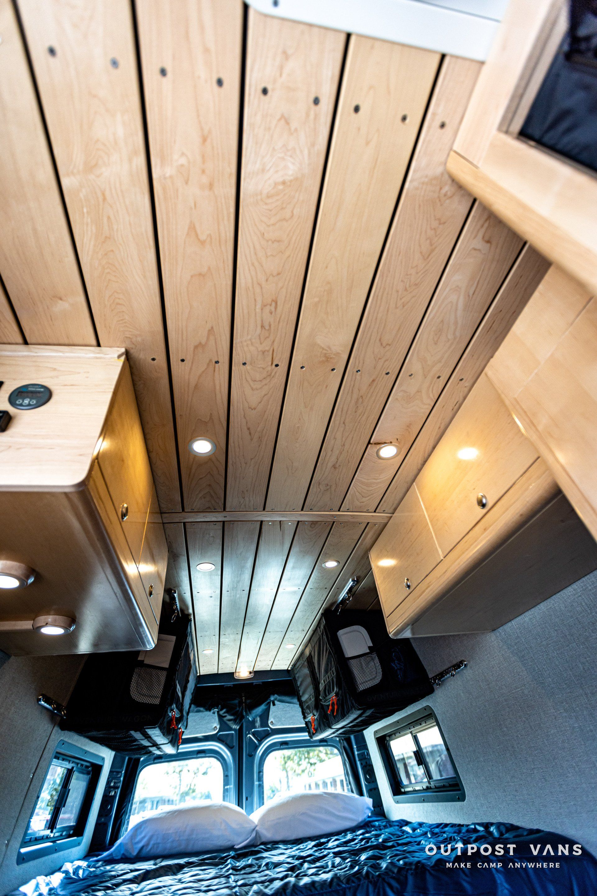 The inside of a van with a wooden ceiling and a bed.